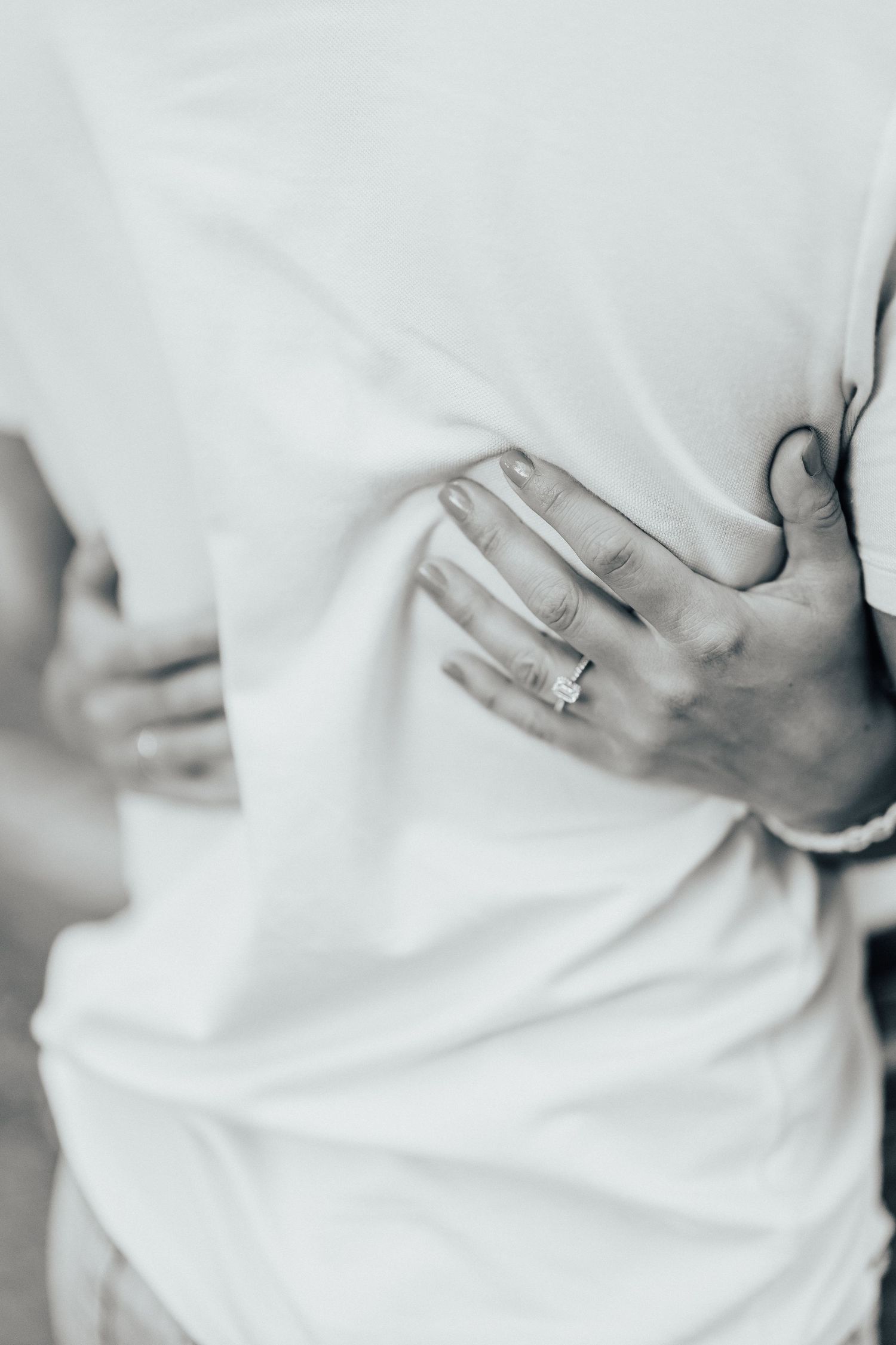 Close-up view of white fabric with a person's hand resting against it showing subtle texture details.