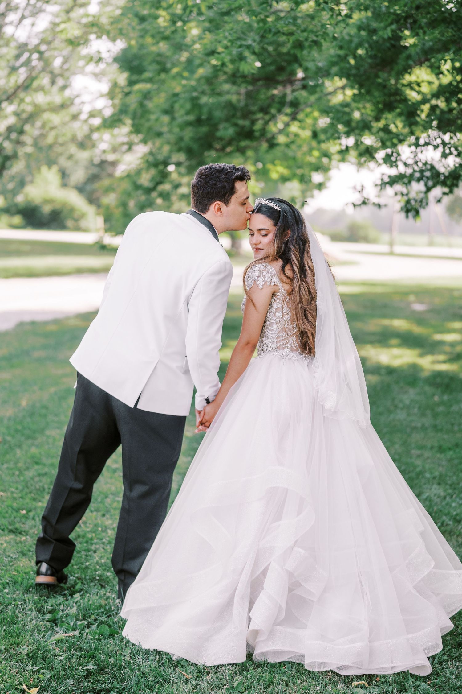 A romantic garden wedding photoshoot featuring a flowing white ballgown and veil in a serene outdoor setting.
