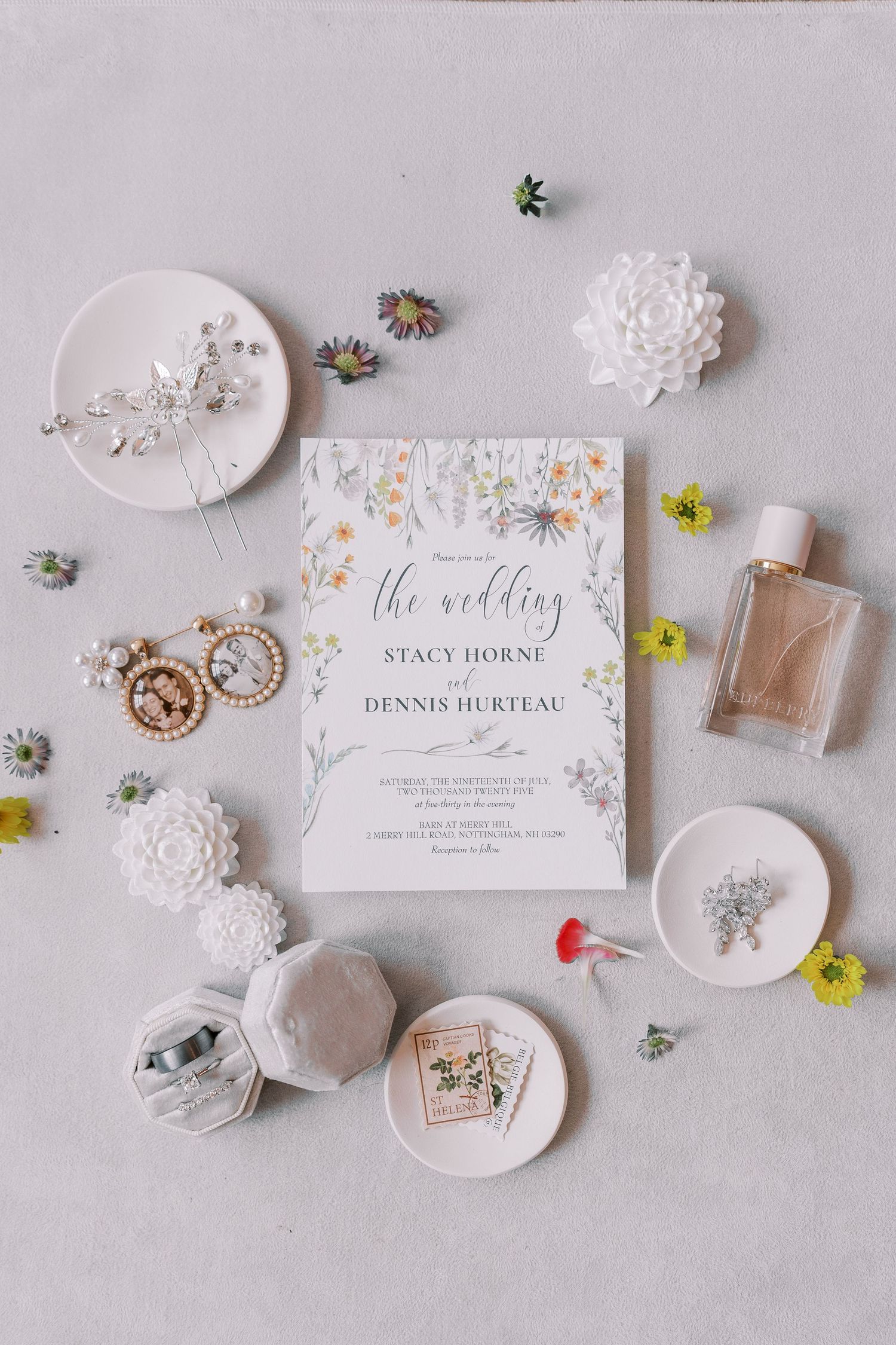 Wedding invitation with floral details surrounded by delicate accessories and decorative elements on a light background.