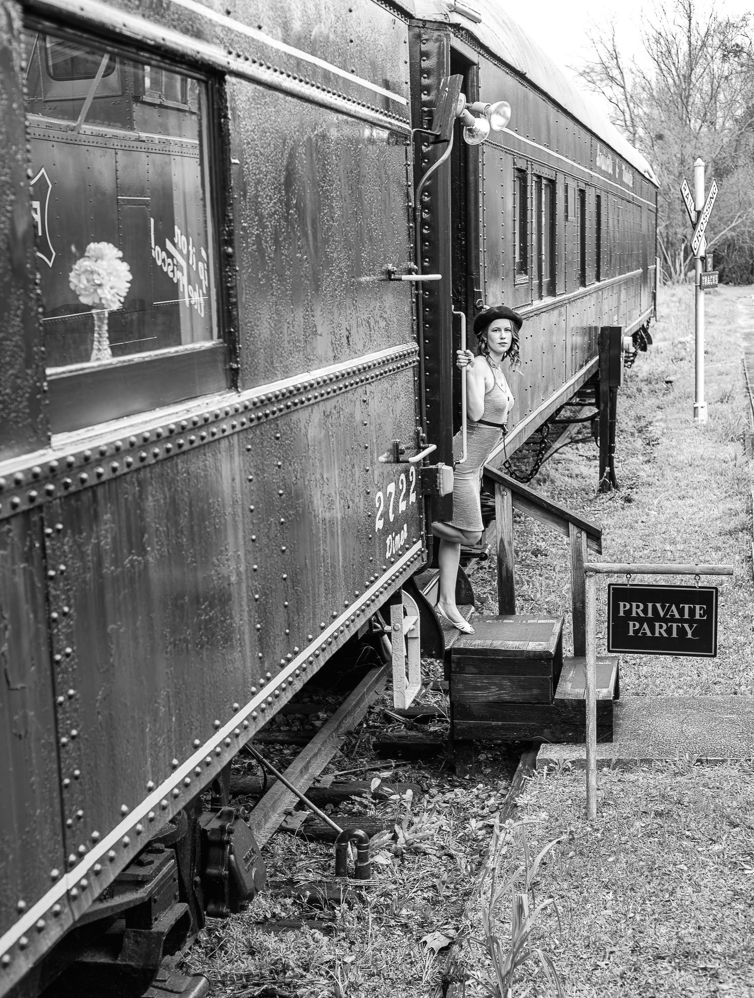 Black and white historical photo of vintage train car with person on steps.