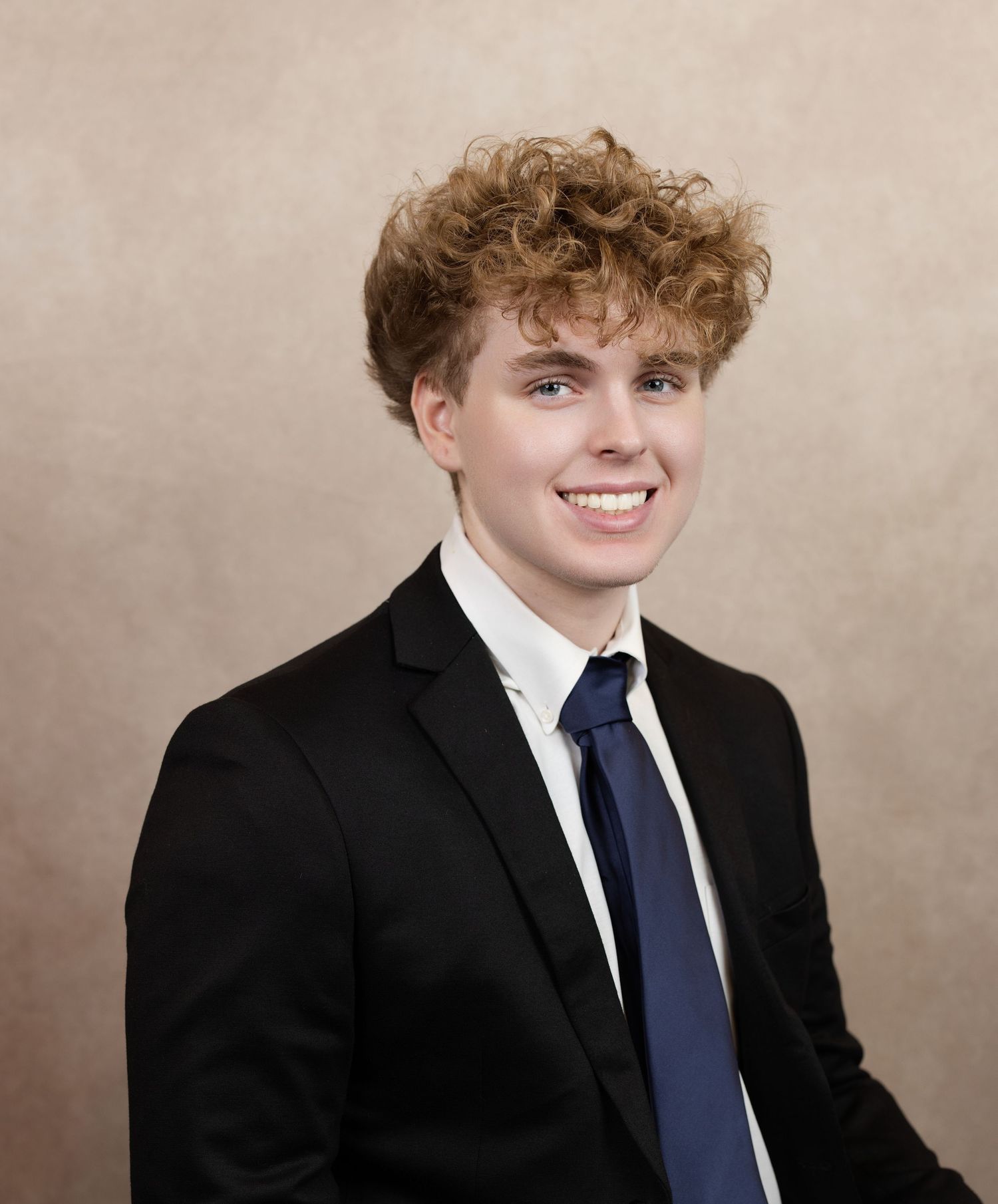 Professional studio portrait series showing different poses in formal attire with navy tie against neutral backdrop.