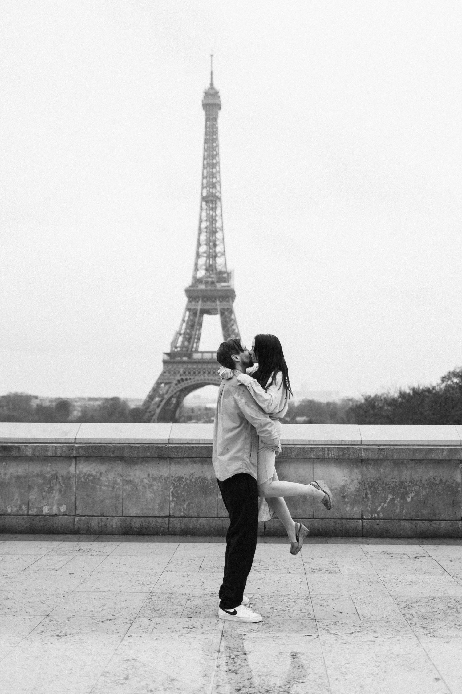Romantic black and white moment captured in front of the Eiffel Tower in Paris.
