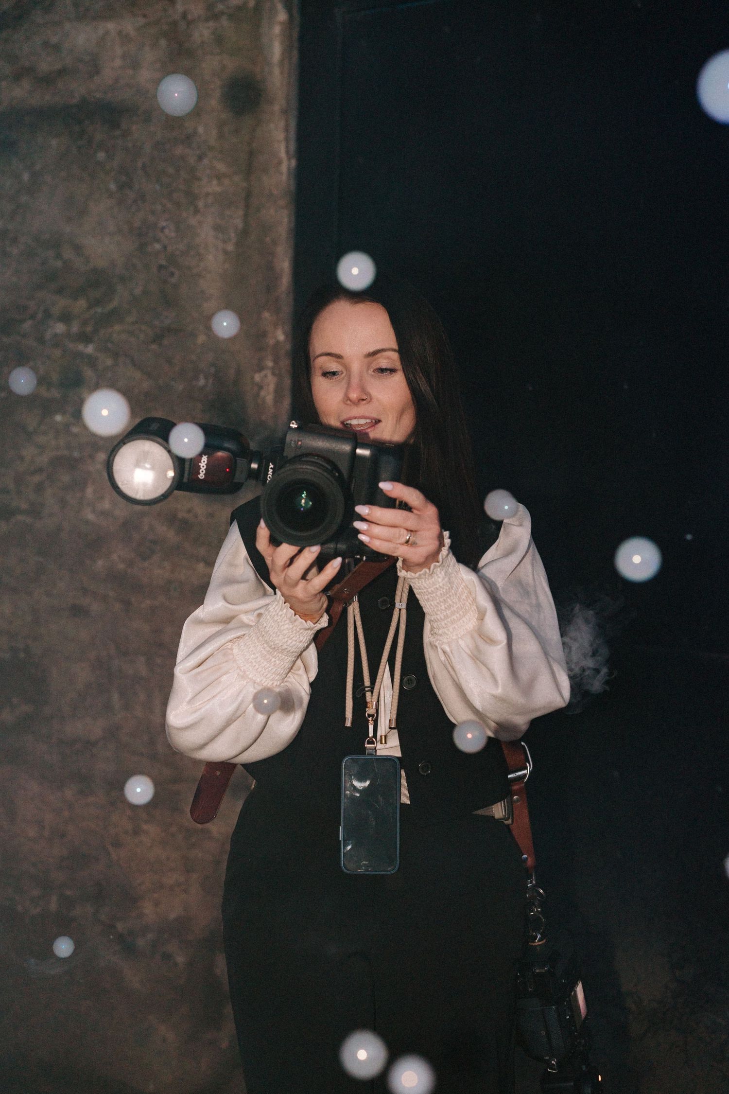 Professional photographer capturing moments with a camera while bokeh lights dance in the background.