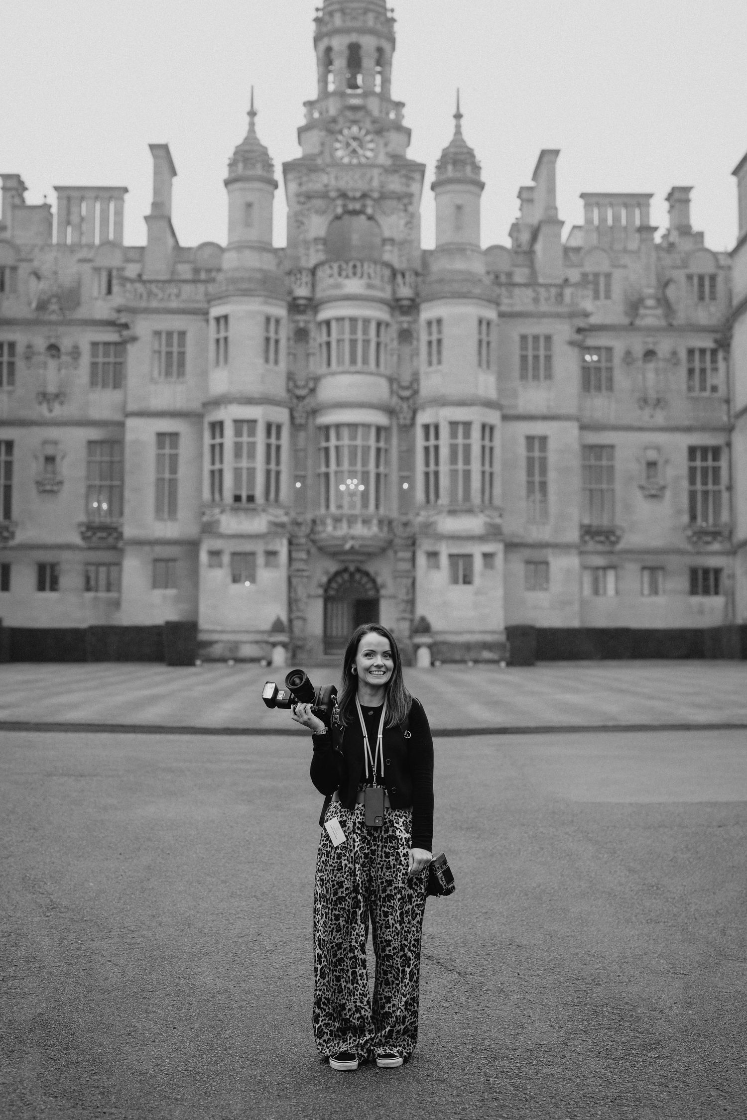 Classic black and white photograph in front of a grand historic mansion with ornate architecture.