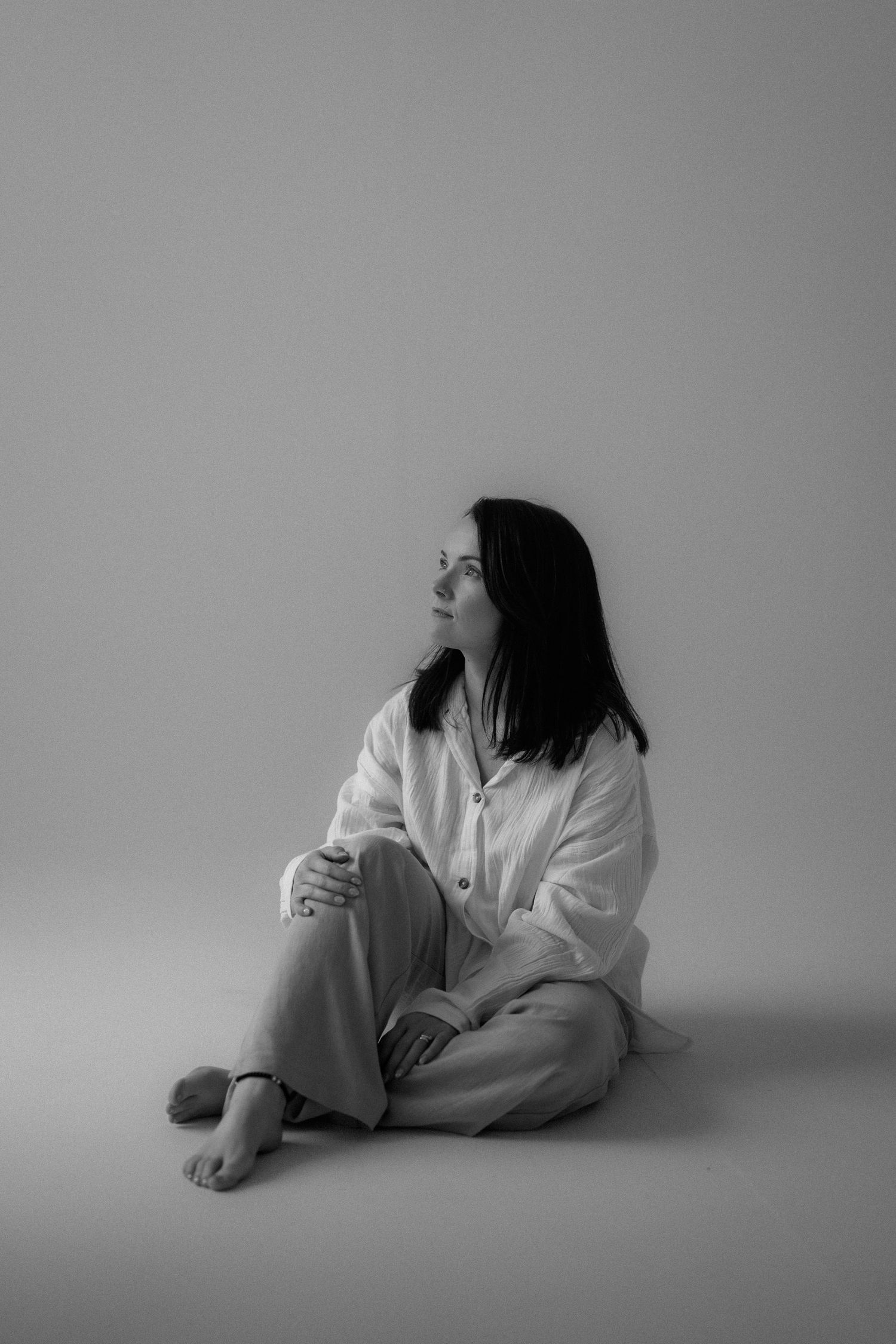 Minimalist black and white portrait in a simple studio setting.