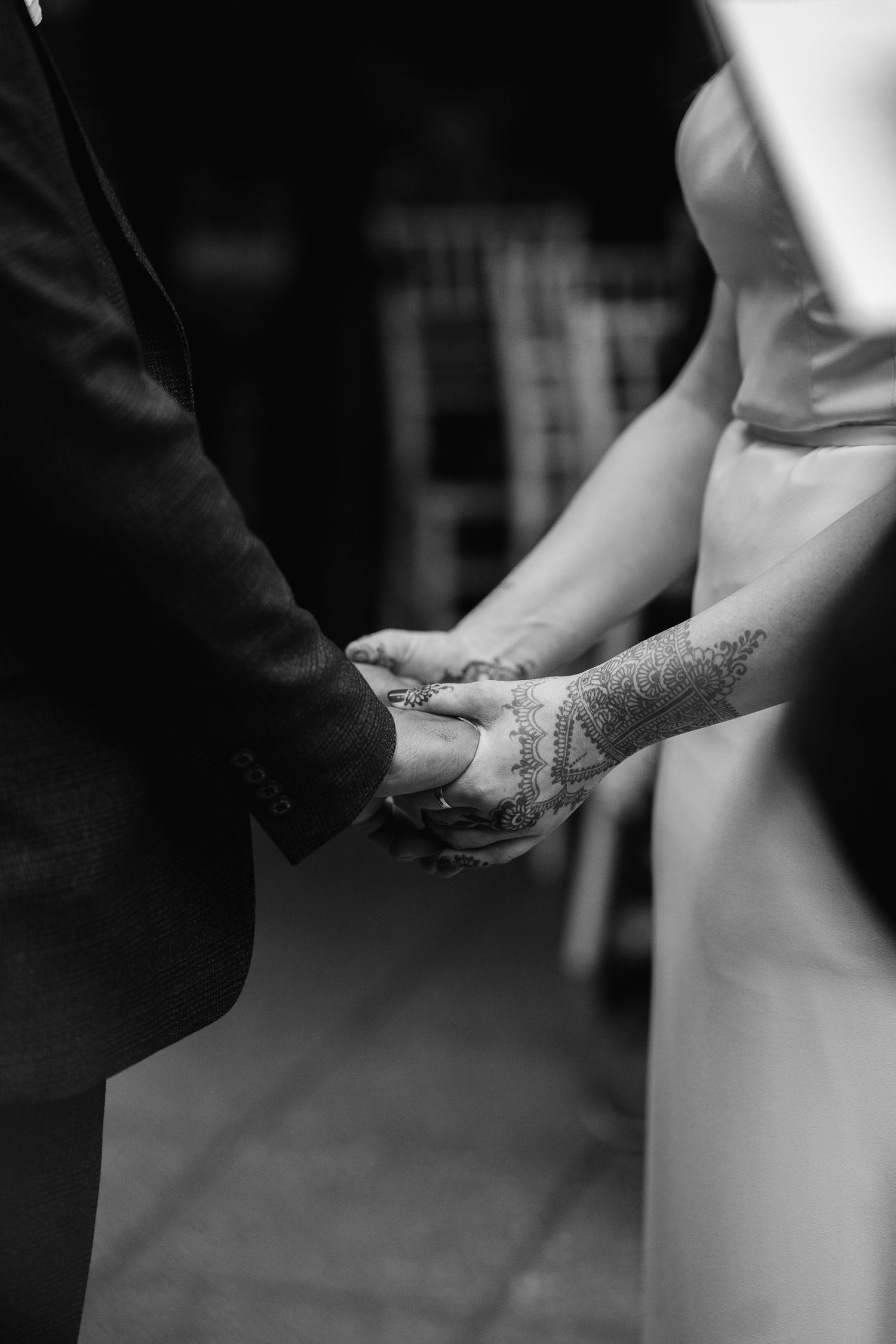 Black and white close-up of hands joining during a wedding ceremony with delicate lace details at The Glasshouse in Leamington Spa.