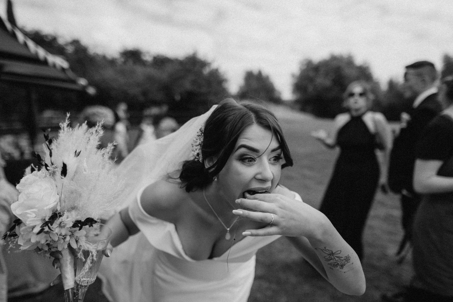 Wedding couple embraces joyfully at outdoor celebration surrounded by guests and nature. Wedding photography at Willow Marsh Farm.