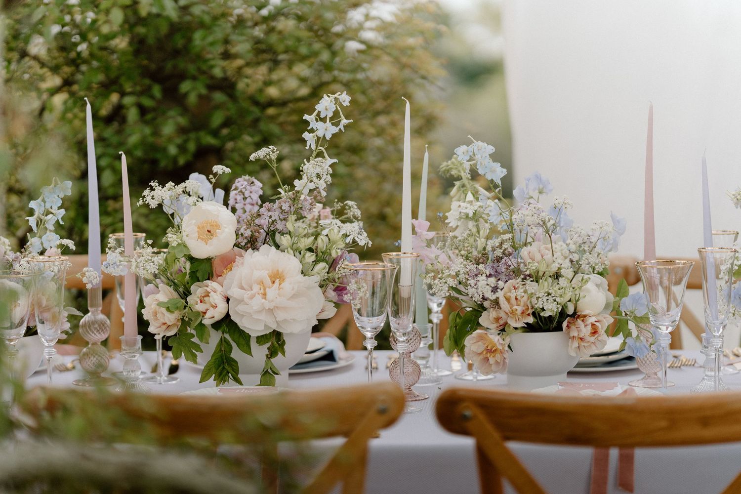 Intimate wedding table setting with blush roses, delicate glassware, and tall white candles.
