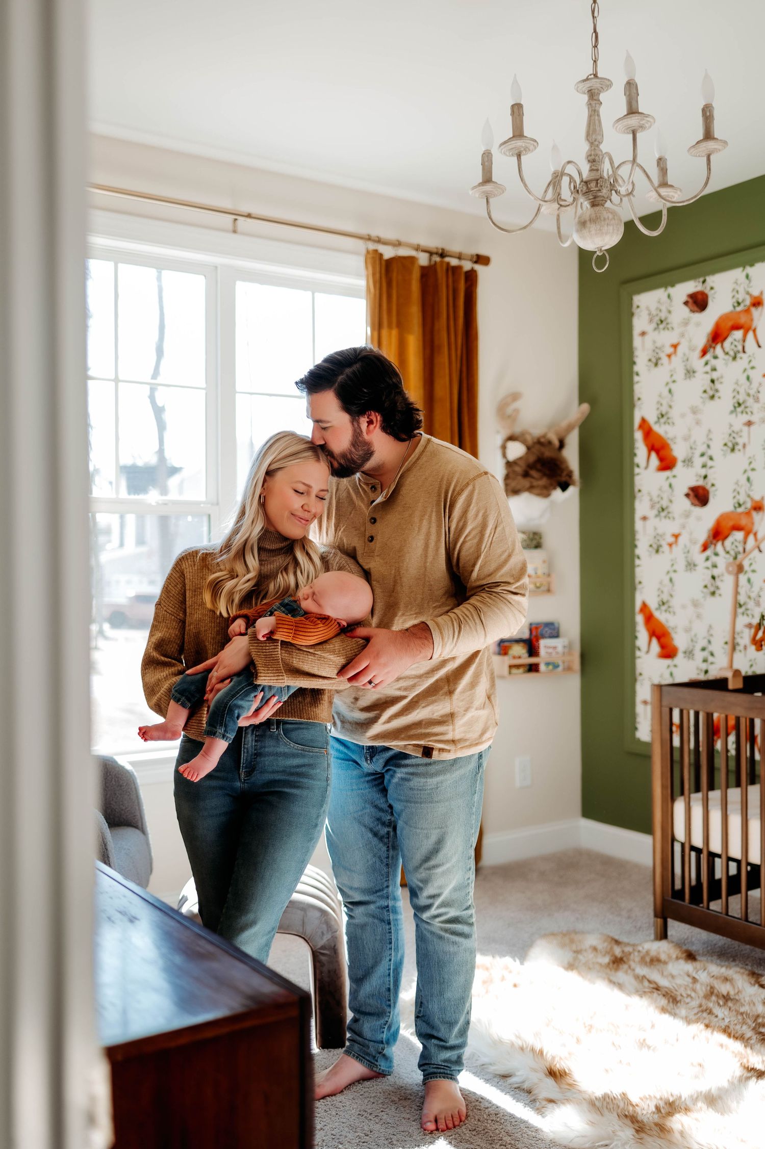 A cozy nursery scene with green walls, floral wallpaper and a vintage chandelier with best newborn photographer wake forest nc
