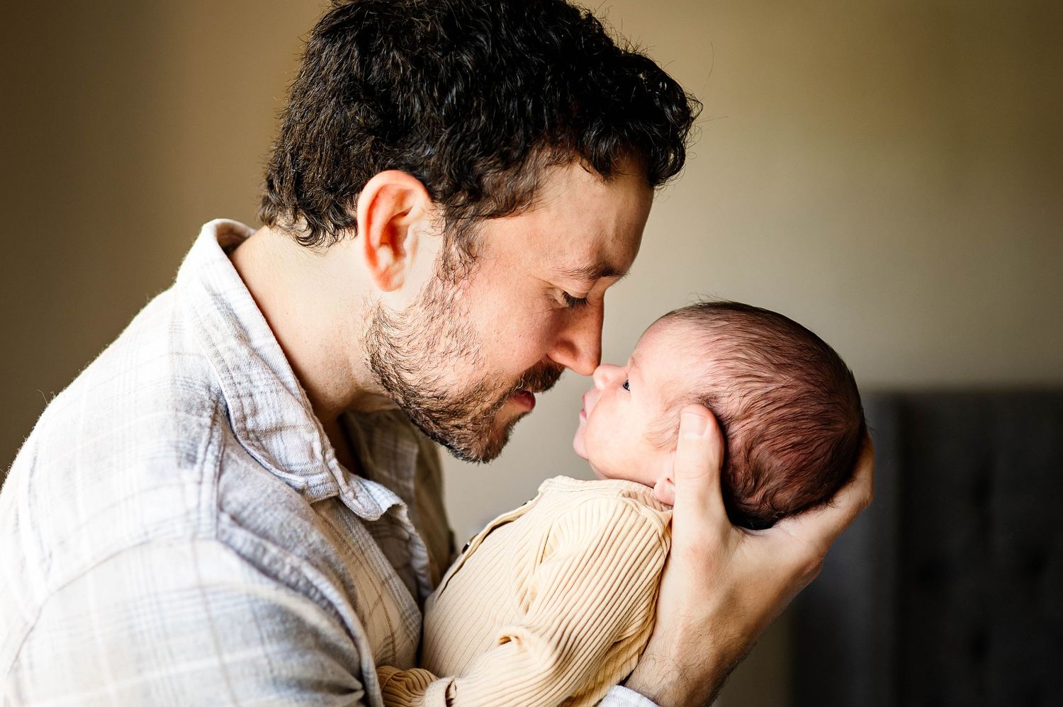 A tender moment between a father and newborn son touching noses with best apex nc newborn photographer