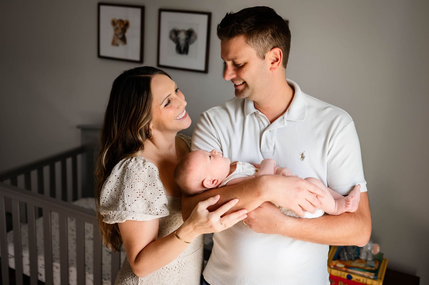New parents share a tender moment with their sleeping baby in a cozy nursery with durham newborn photographer