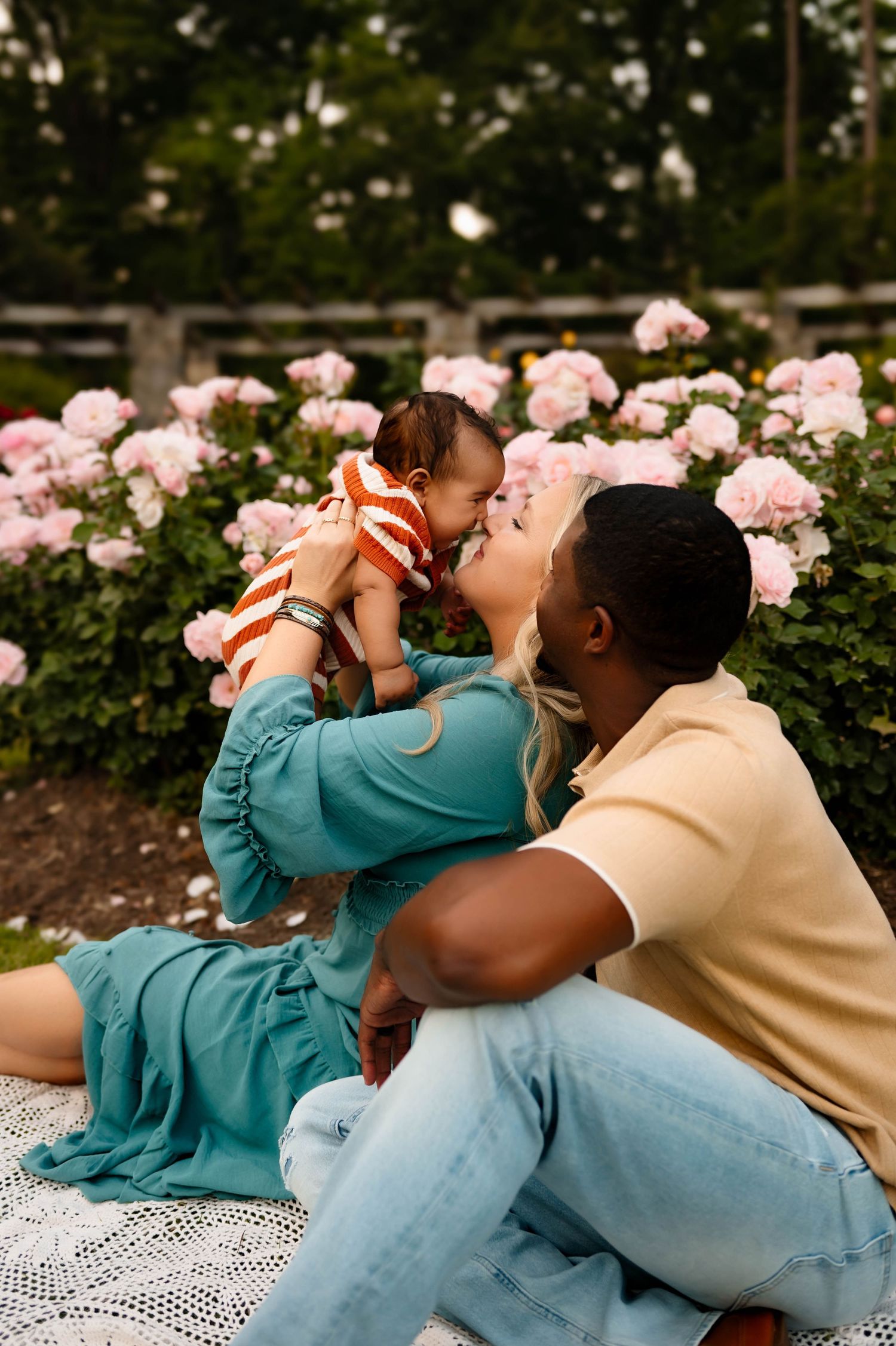A loving family moment captured on a picnic blanket in a garden setting during newborn photography session in raleigh nc
