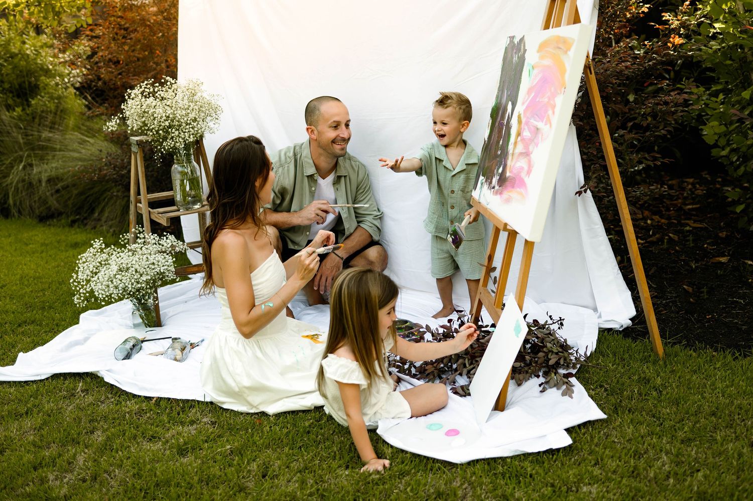 Family laughs while painting and enjoying creative outdoor photography session with a raleigh family photographer