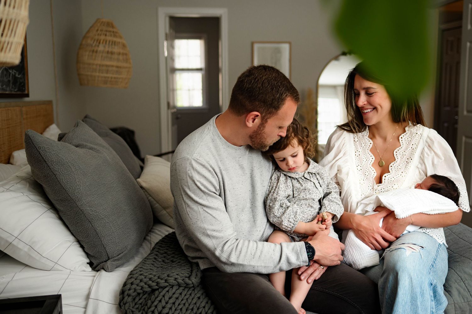 A family shares a tender moment together in a cozy master bedroom during in home newborn photography raleigh nc
