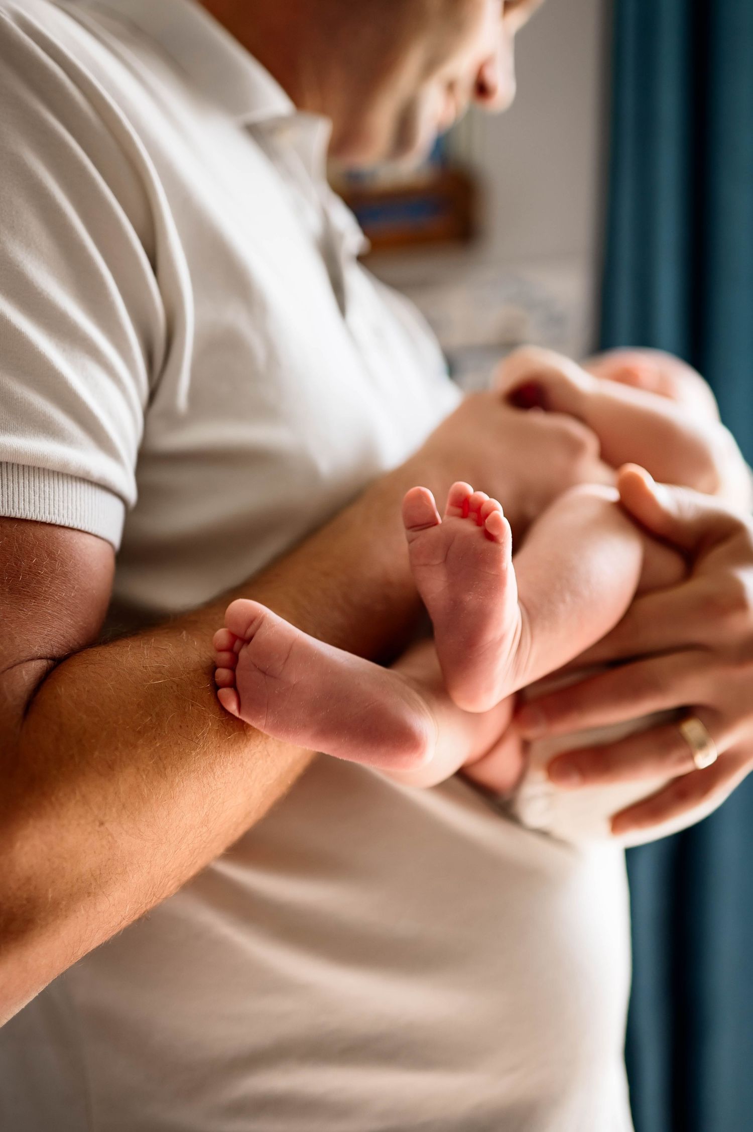 Close up photo of tiny newborn baby feet and toes being cradled by father's hands with the best durham newborn photographer