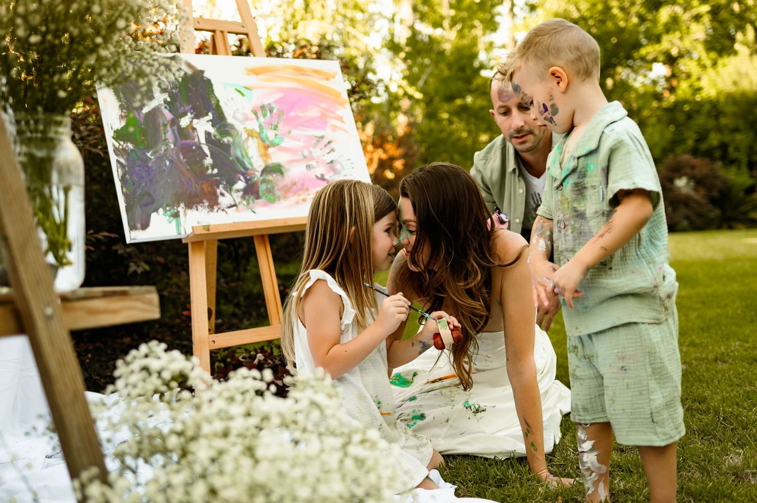 Family painting together during an outdoor family photography shoot in their backyard with durham family photographer