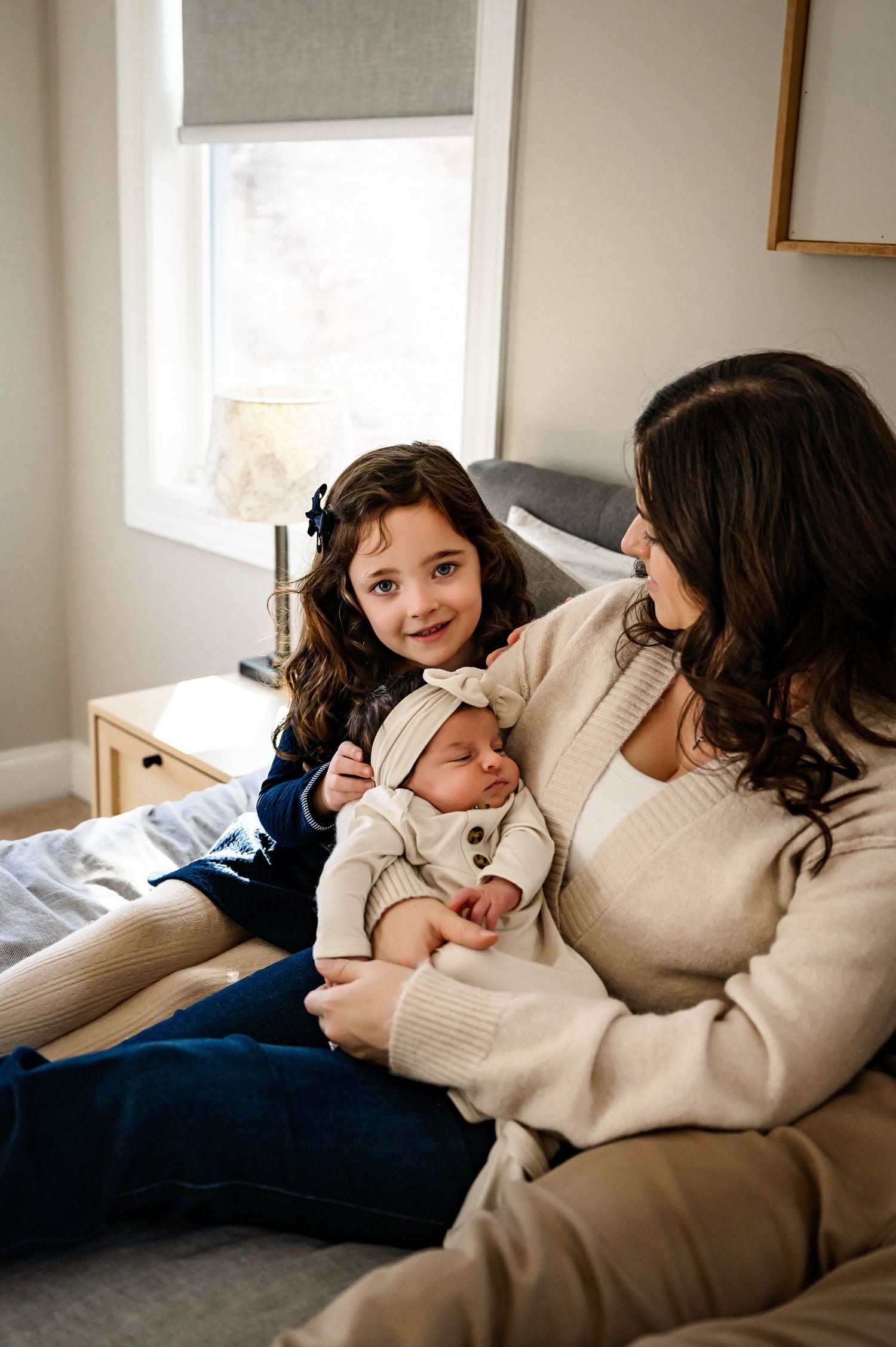 Family relaxing together on sofa at home in during newborn photography session with raleigh newborn photographer