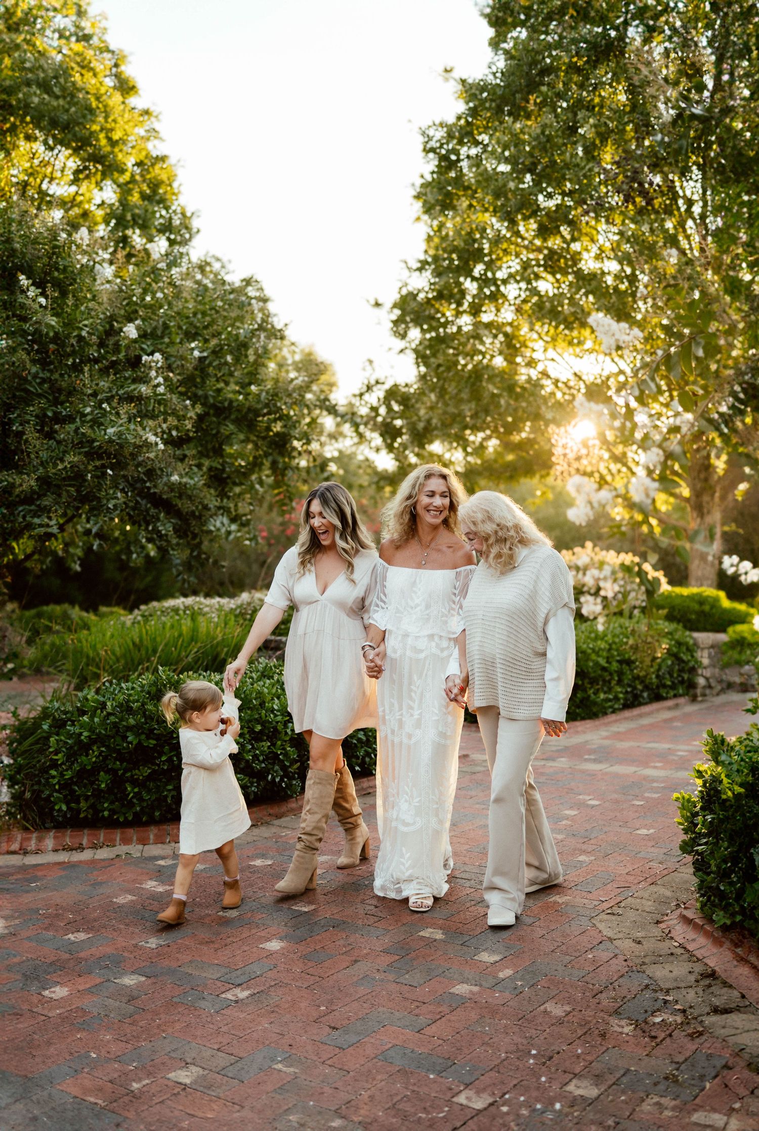 Children and grandparents walking together on a brick path in a garden at sunset with golden sunlight with Emma Branch Photography