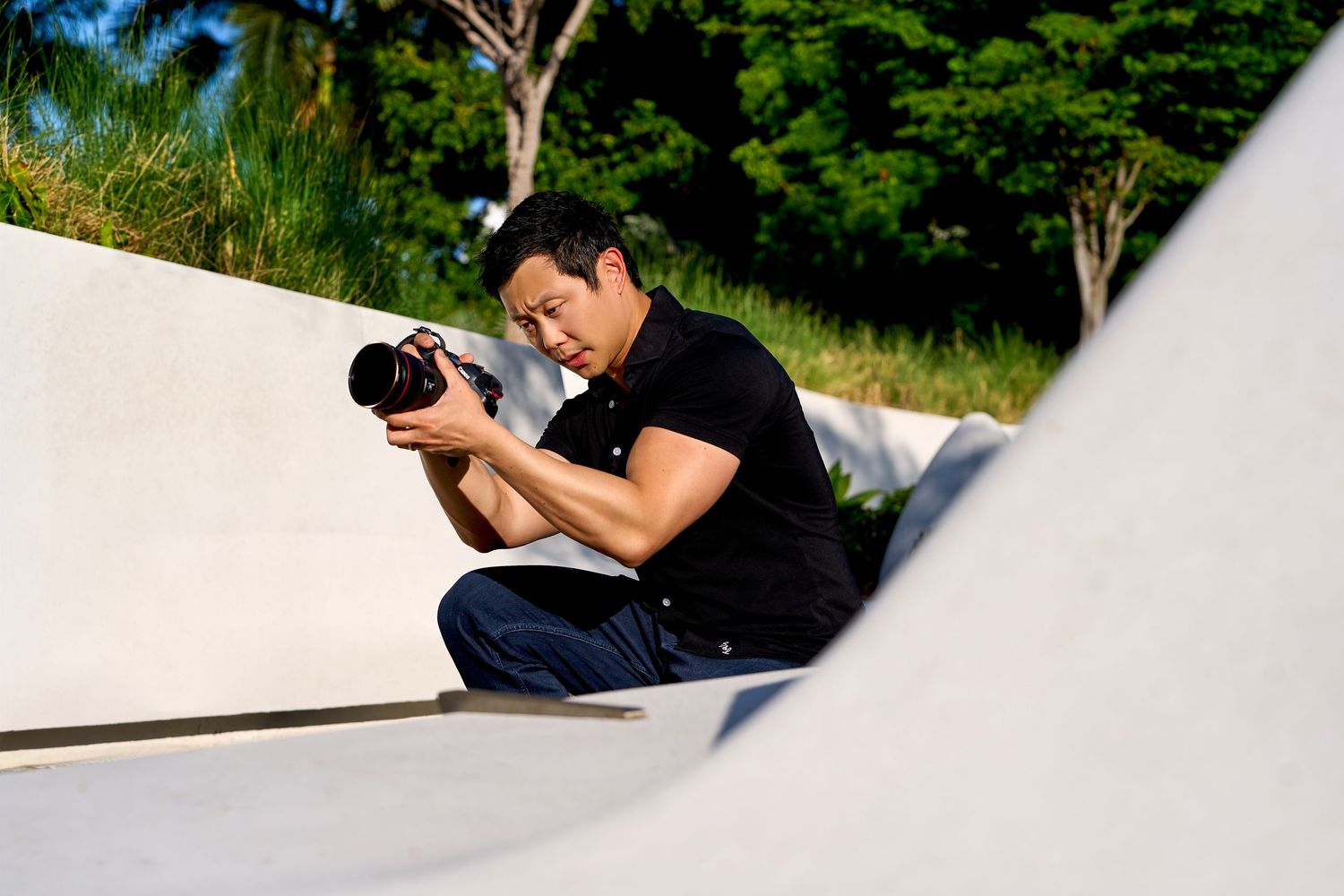 Chris Ha in black shirt capturing shots while positioned on white curved surface.