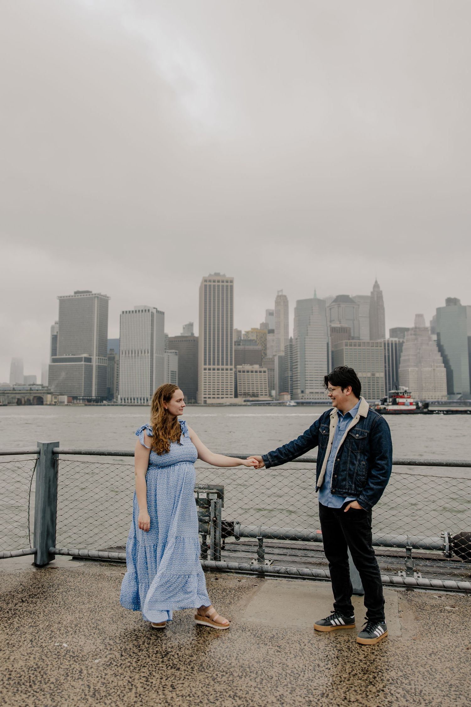 couple holding hands on a foggy day in front of the manhattan sky line