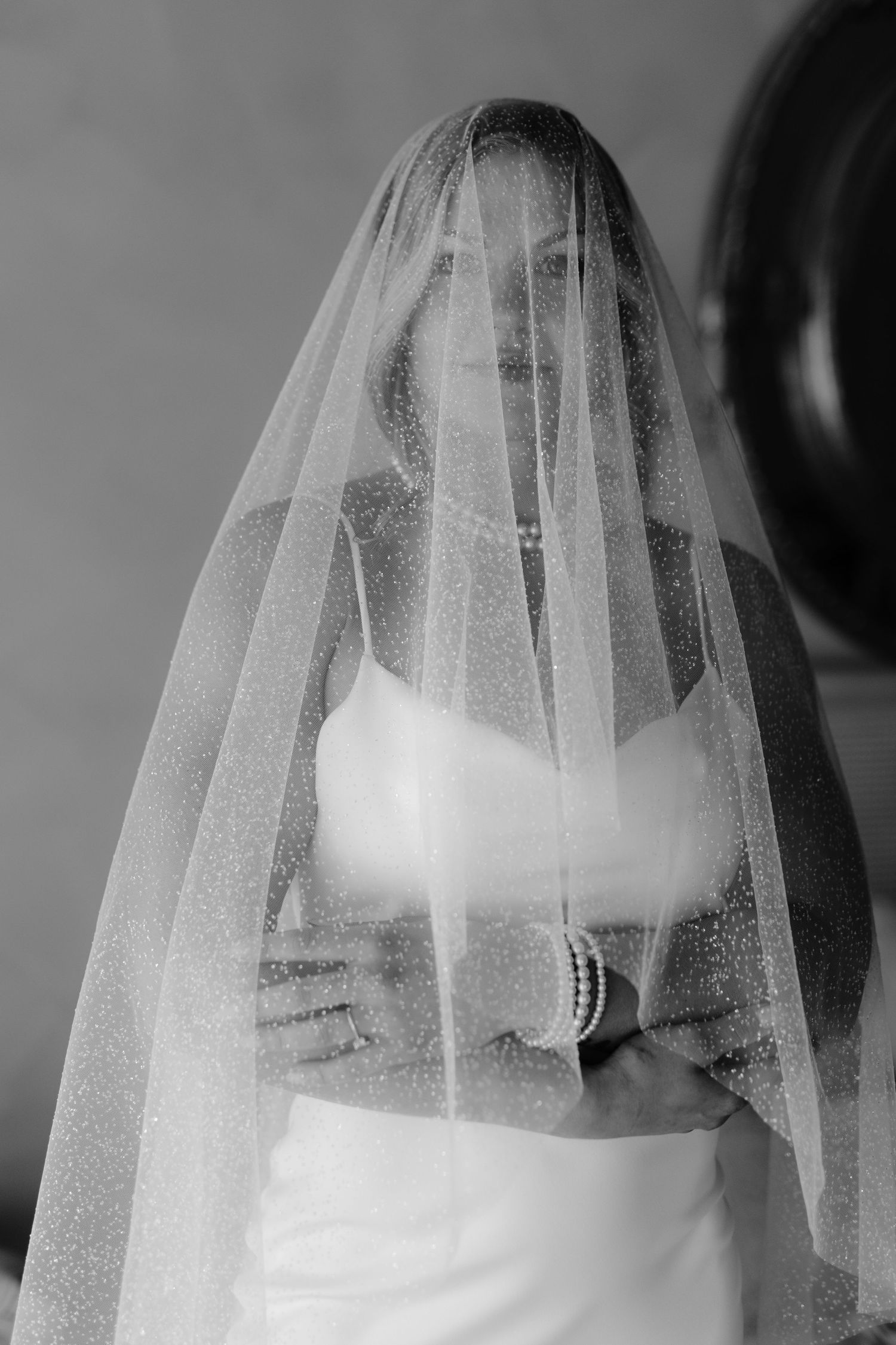 Black and white collage of a bride wearing a delicate tulle veil for wedding portraits.