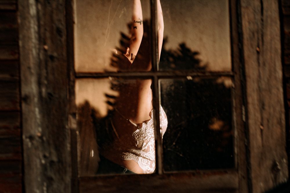 Close-up shot of pointed ballet shoes in front of rustic window at golden hour.
