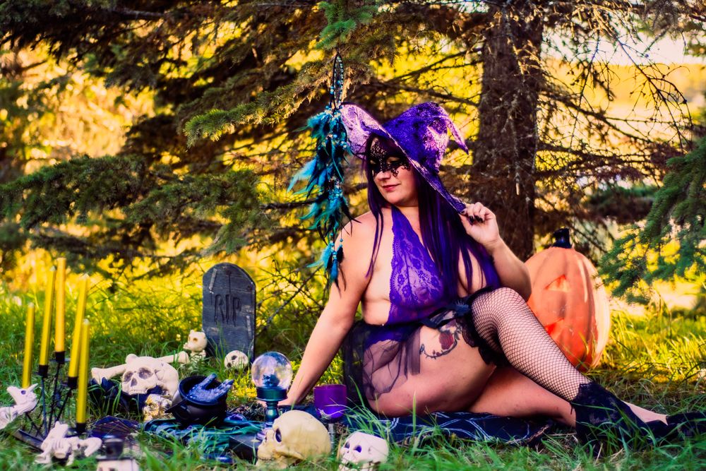Halloween themed outdoor scene with purple witch costume, pumpkins, and spooky graveyard decorations.