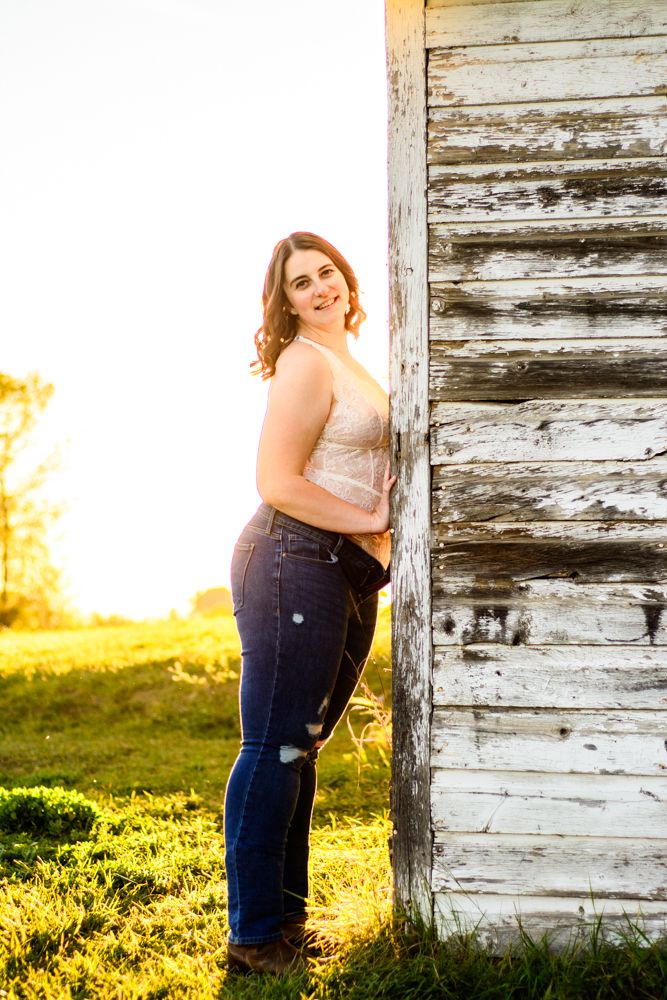 A casual portrait against weathered white barn siding in golden evening light.