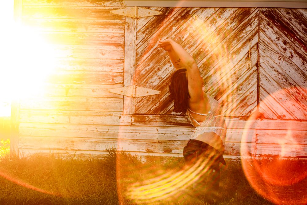 Silhouette in rustic doorway with dramatic lens flare at sunset.