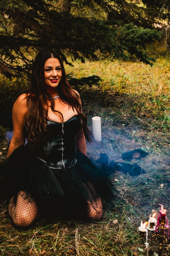 Gothic styled portrait in black corset dress with smoke effects outdoors.