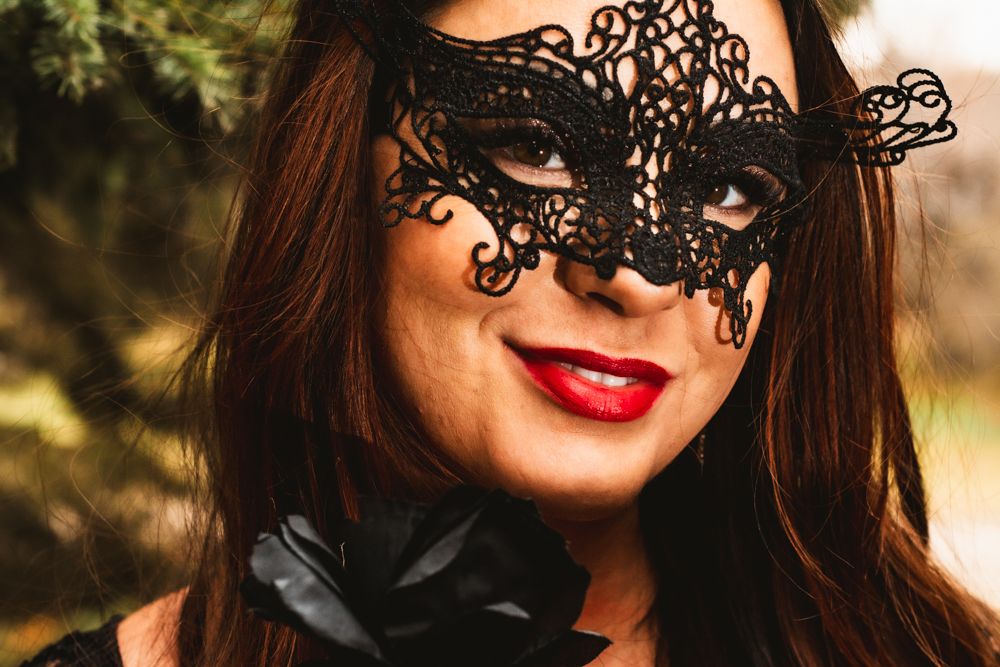 Fantasy portrait wearing elegant black lace mask and red lipstick.