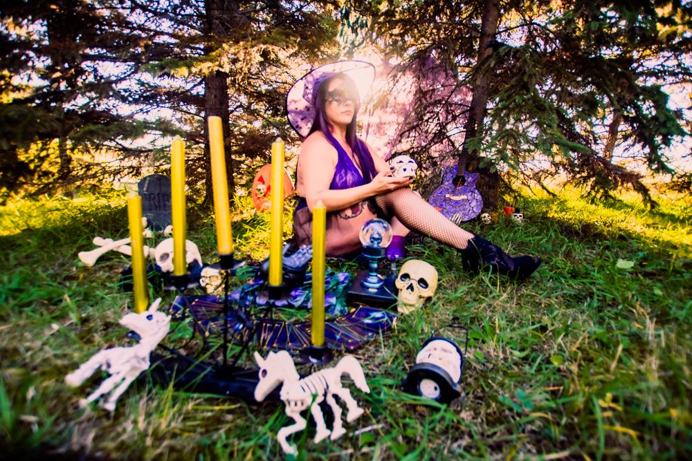 Spooky outdoor halloween setup with candles, skulls and skeleton decorations in forest setting.