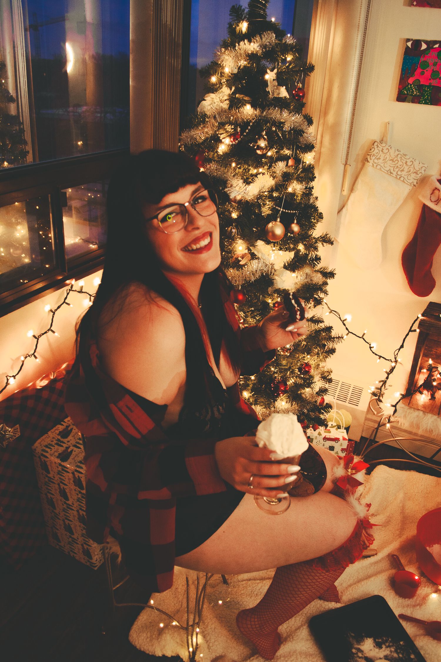 Festive holiday portrait by a decorated Christmas tree with twinkling lights and stockings.