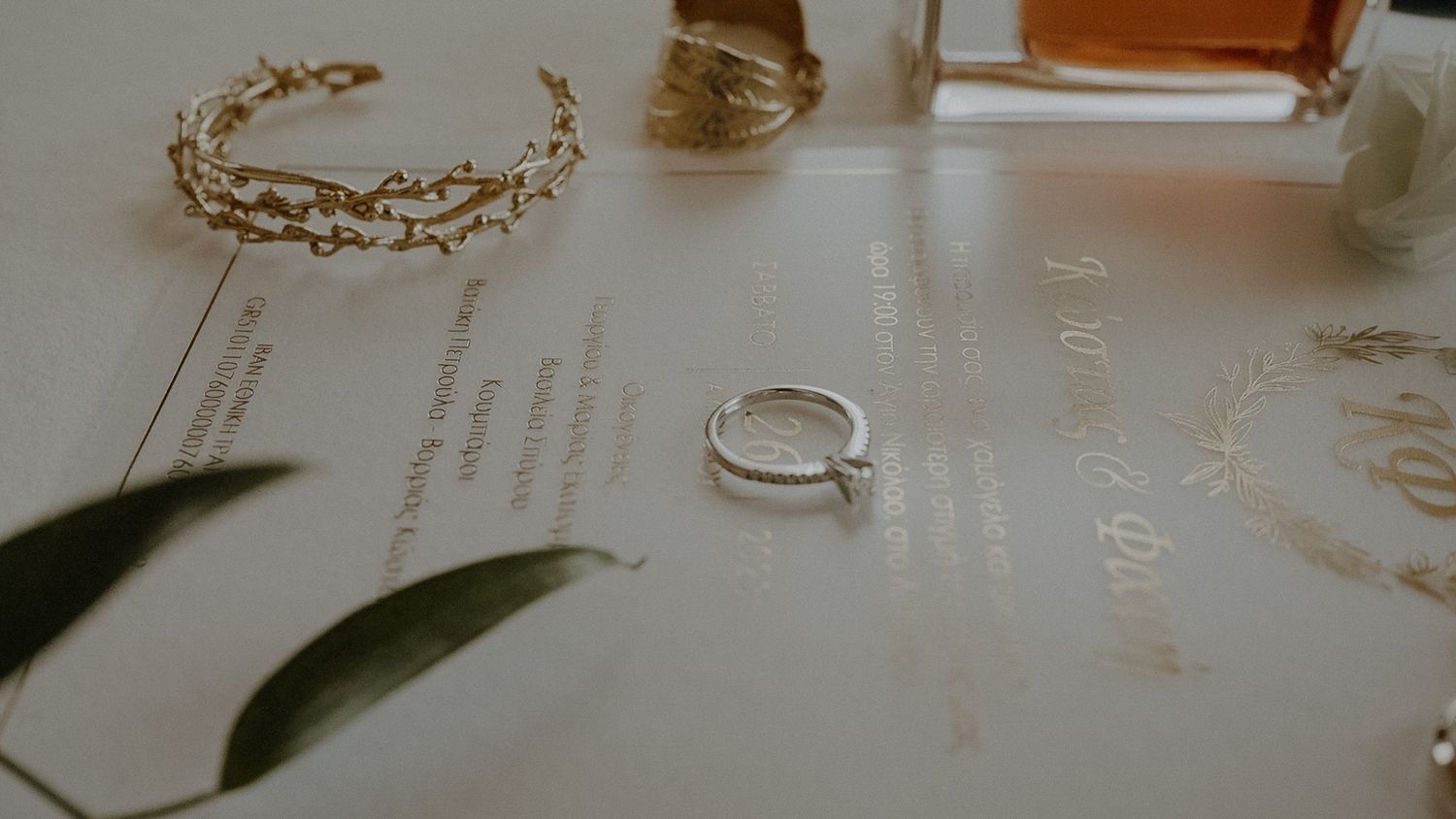 Delicate wedding accessories including a gold crown and ring on a light surface.