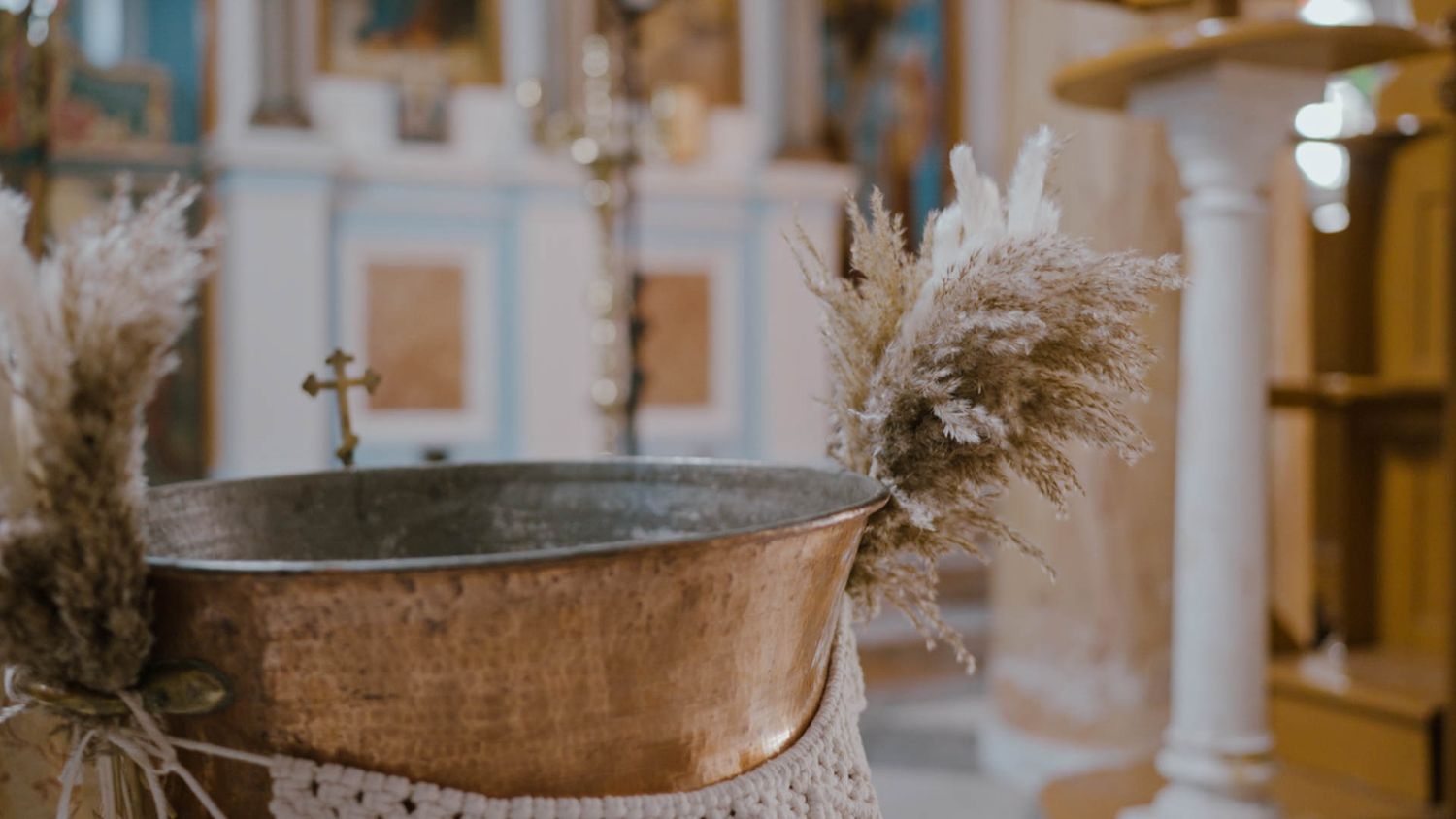 Vintage copper bathtub decorated with pampas grass in an elegant white bathroom interior.