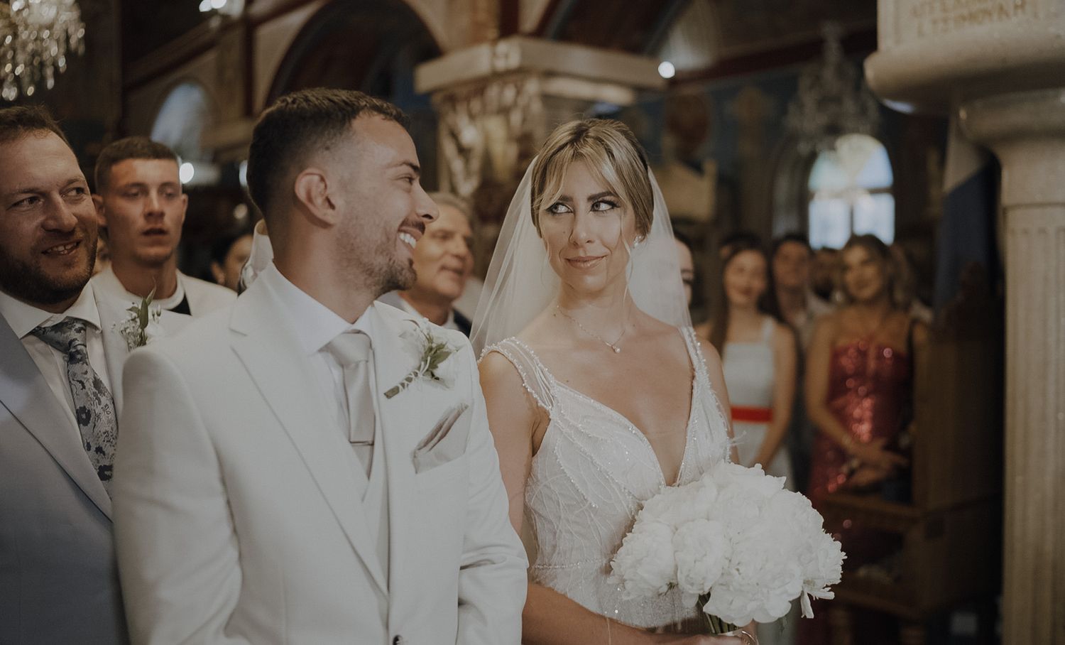 A couple stands together during their wedding ceremony in an elegant church interior.