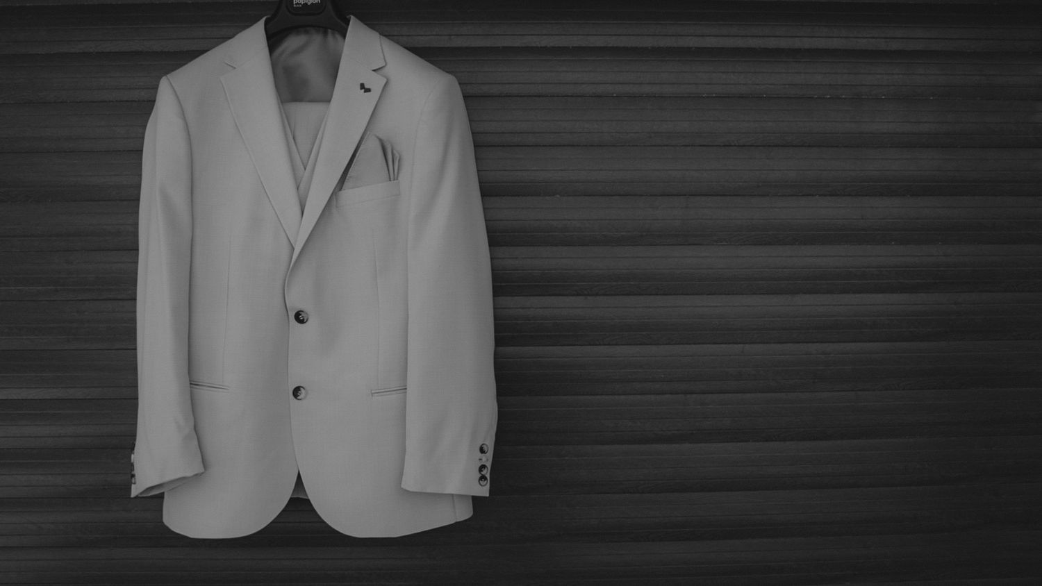 A white blazer jacket hangs on a dark wall, creating a striking monochromatic contrast.