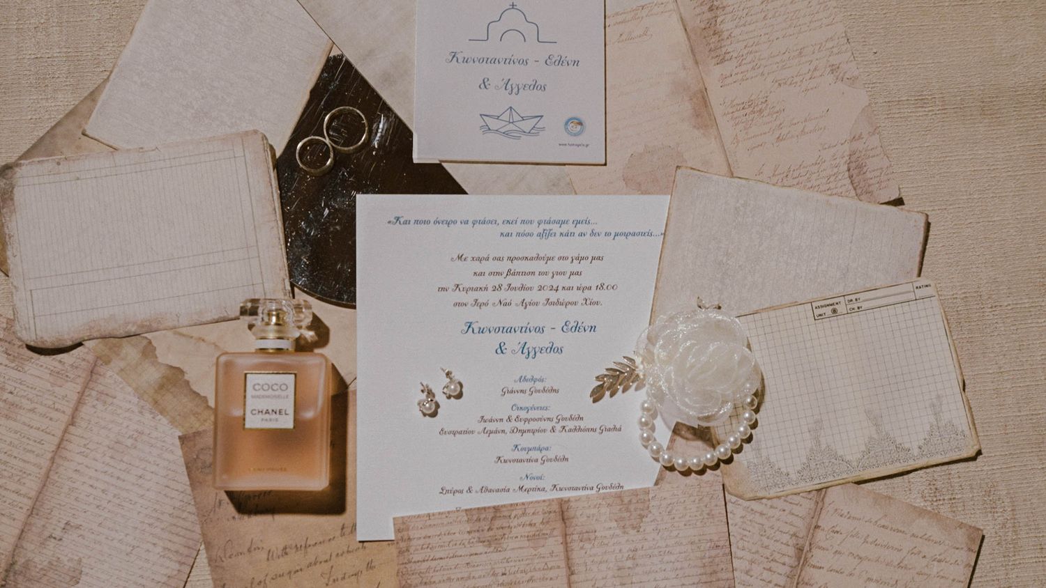 Perfume bottle and wedding invitation with delicate accessories arranged on cream-colored fabric in vintage style.