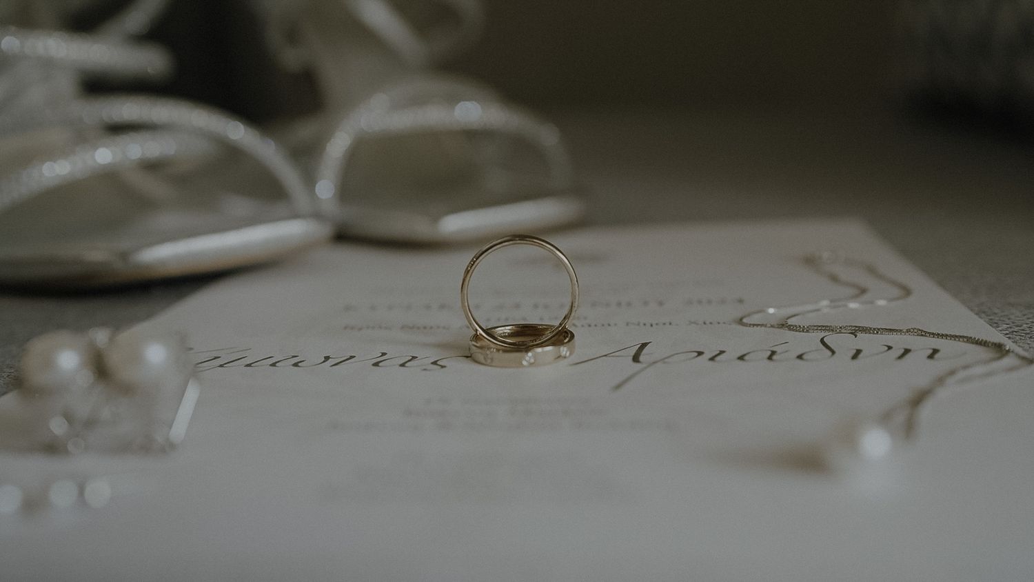 A delicate gold wedding ring rests on a sheet of paper with elegant writing.