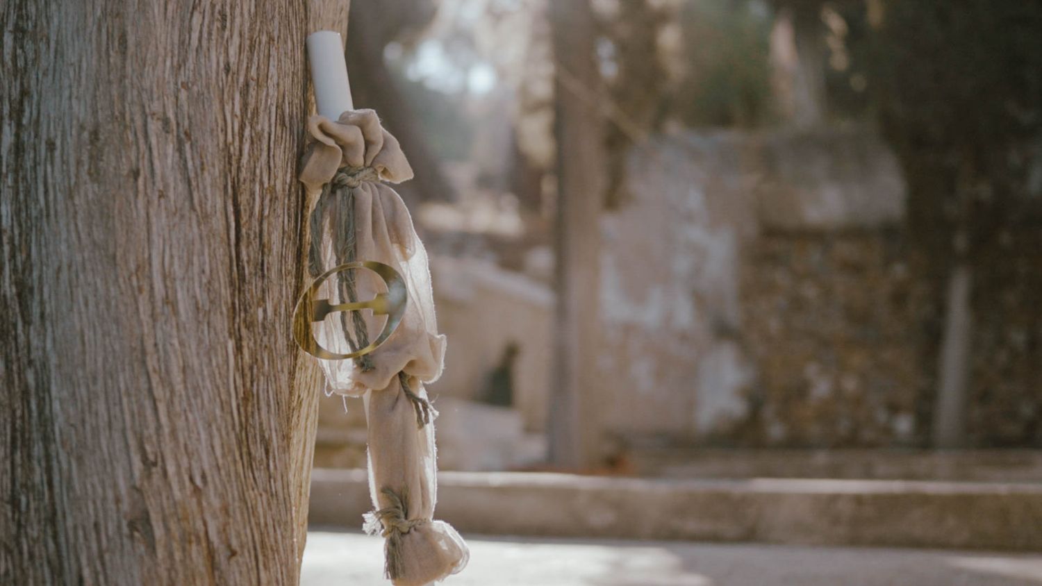 A wooden puppet hangs from a string against a tree trunk in soft, dreamy lighting.