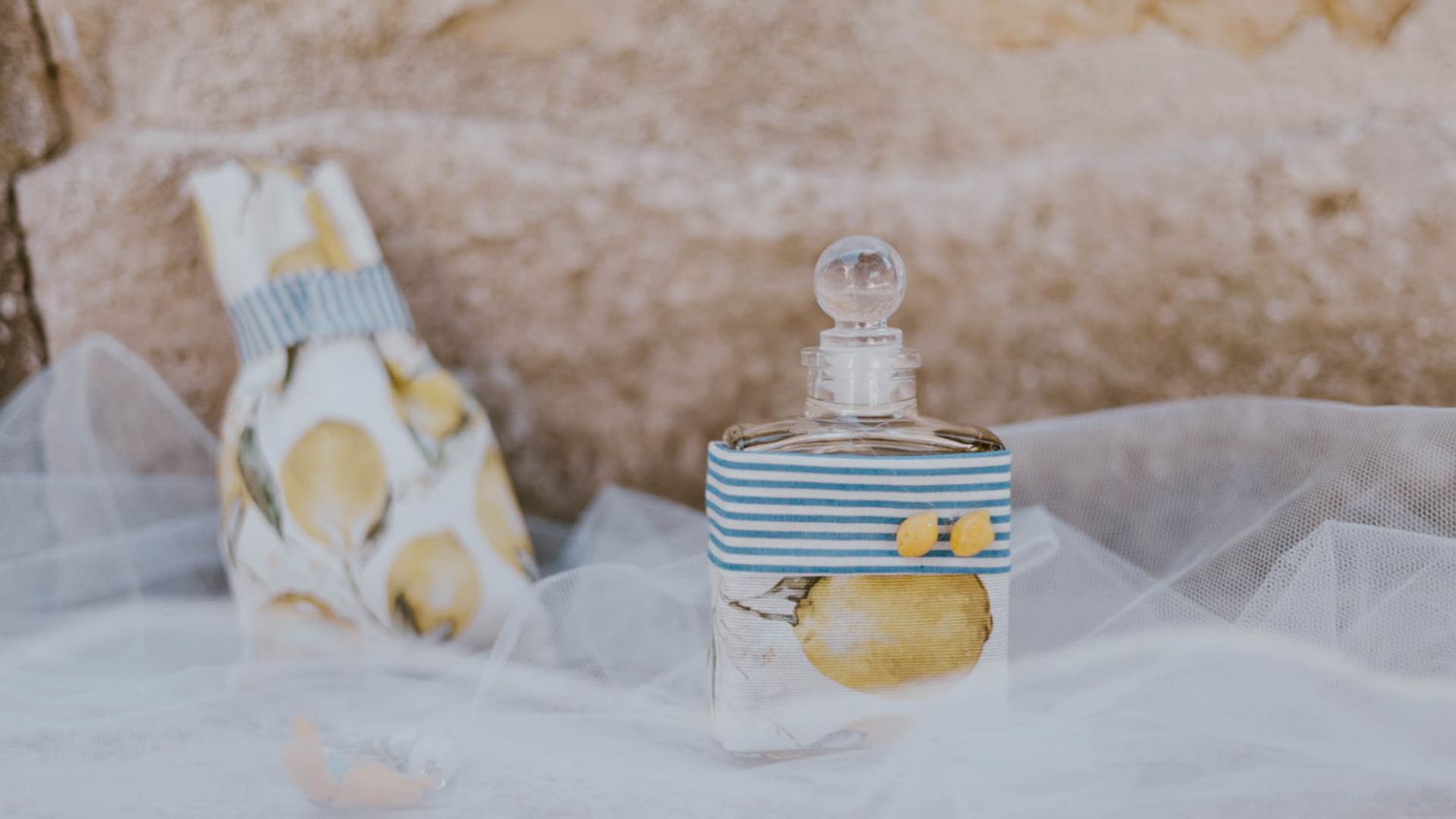 Vintage perfume bottles with crystal stoppers arranged on soft tulle fabric against a textured beige background.