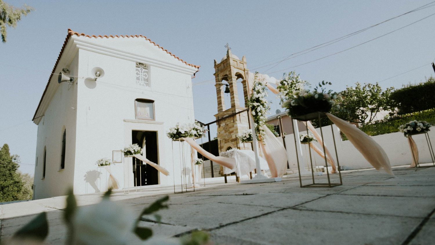White Mediterranean chapel with bell tower and steps stands against blue sky on a sunny day in Portugal.