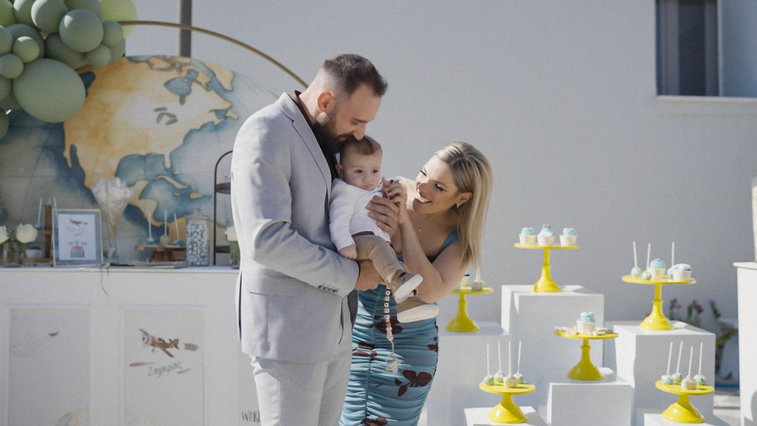A family stands together celebrating with yellow and pastel decorations.