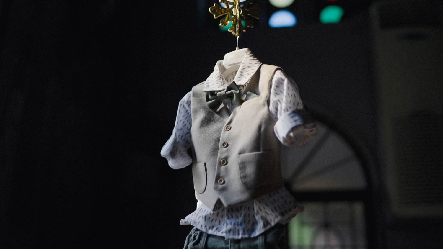 A close-up of a white dress shirt with a black bow tie on display in low light conditions.