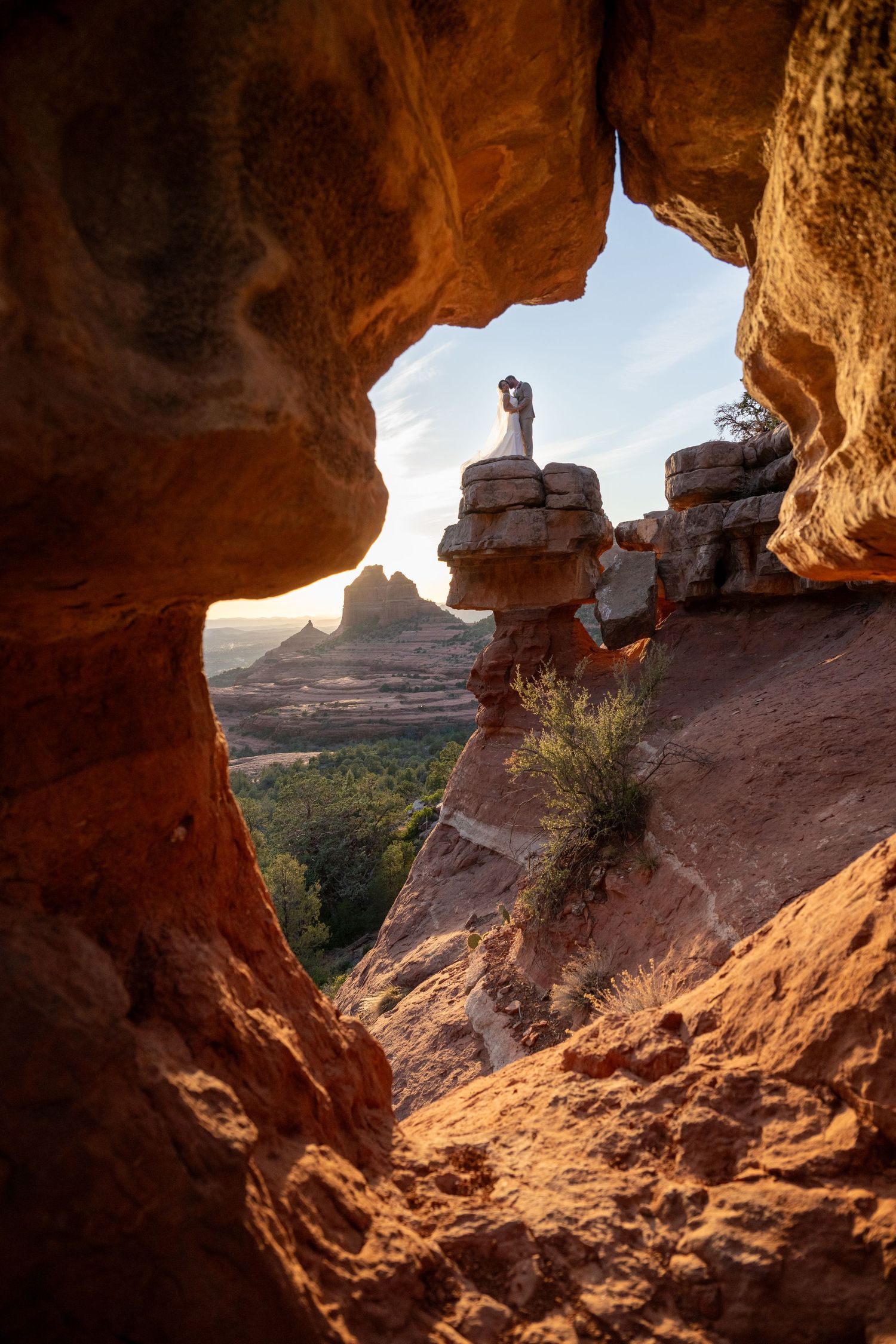 A stunning view through a natural rock arch in Moab, Utah, framing silhouettes on a rock formation at sunset.