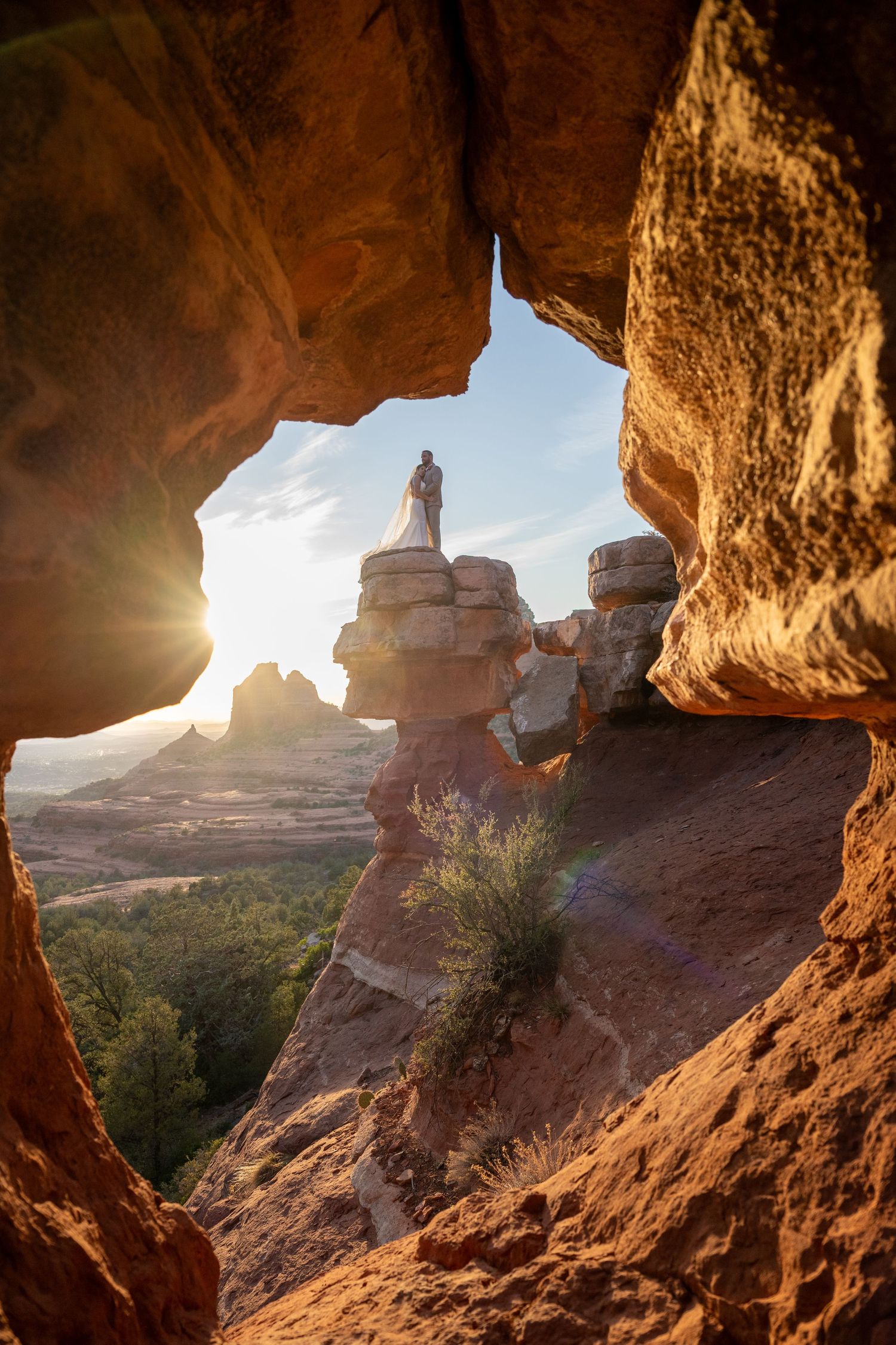 Scenic desert landscape viewed through a natural rock arch at sunrise with silhouetted rock formations in Utah wilderness.