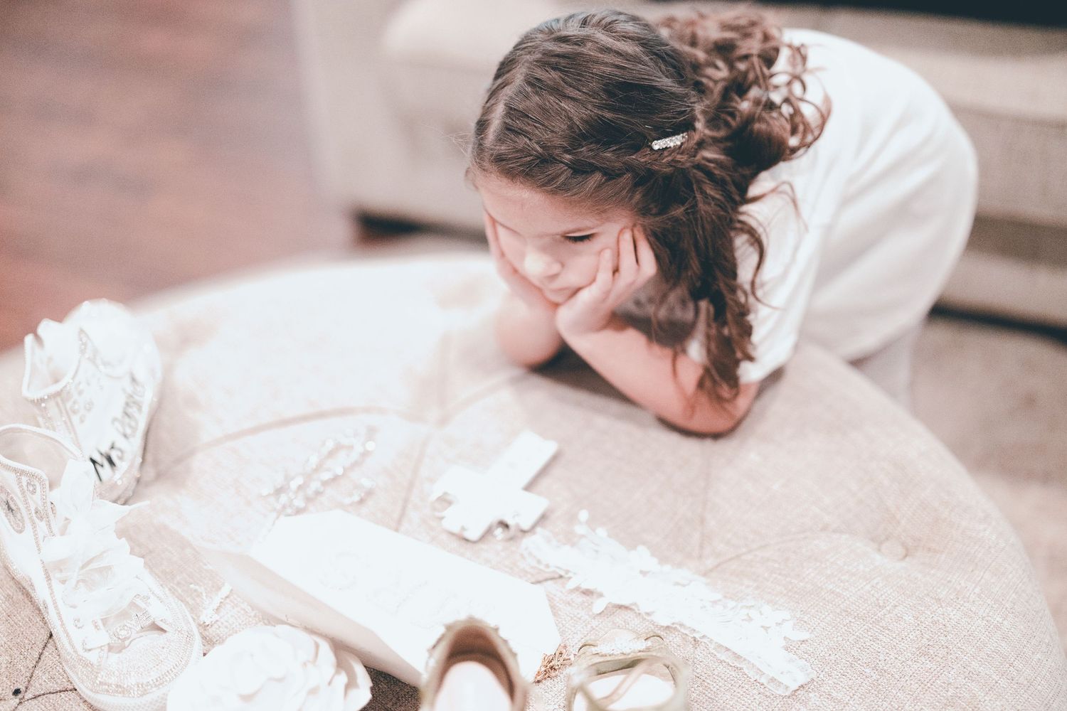 Someone lies on a carpet surrounded by scattered papers while resting their head in their hands.