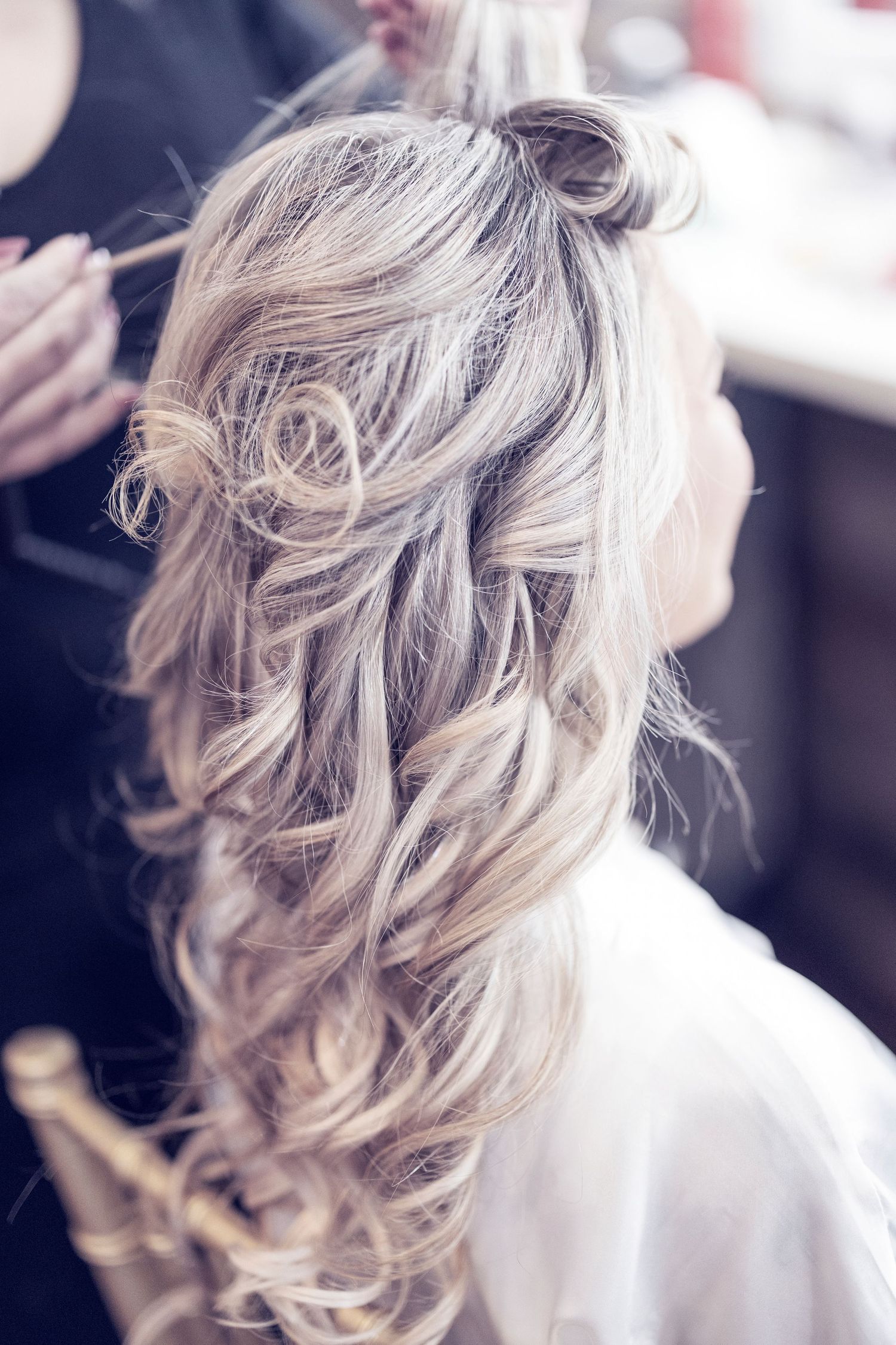 Elegant hairstyle featuring long wavy platinum blonde hair styled in loose cascading curls for a wedding or formal event.
