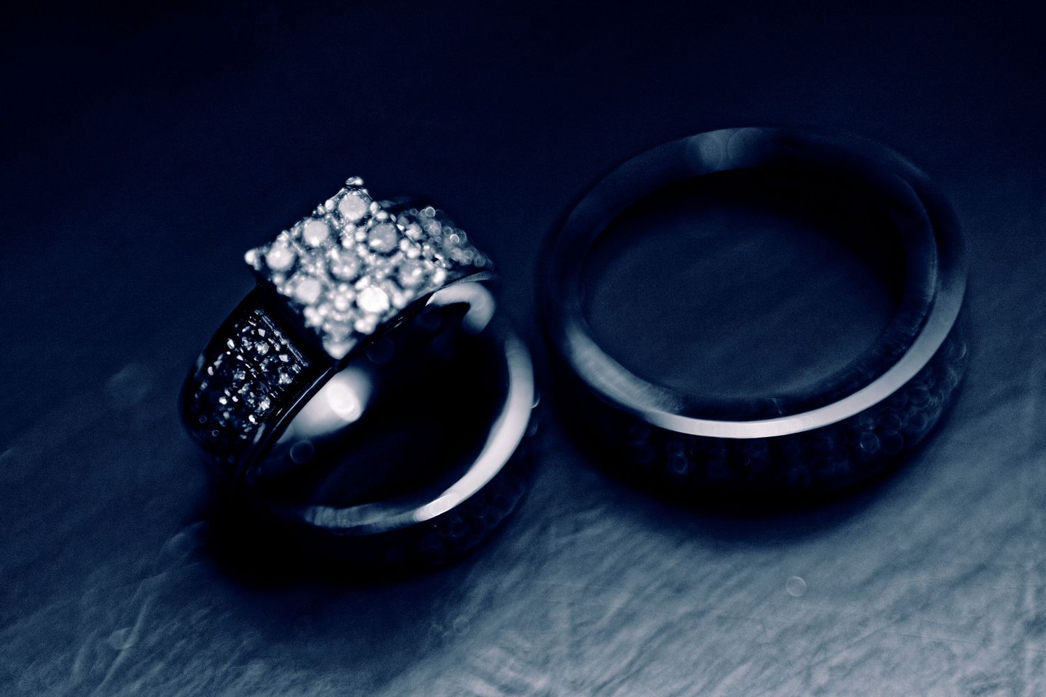 An elegant diamond engagement ring and wedding band set photographed against a dark background.