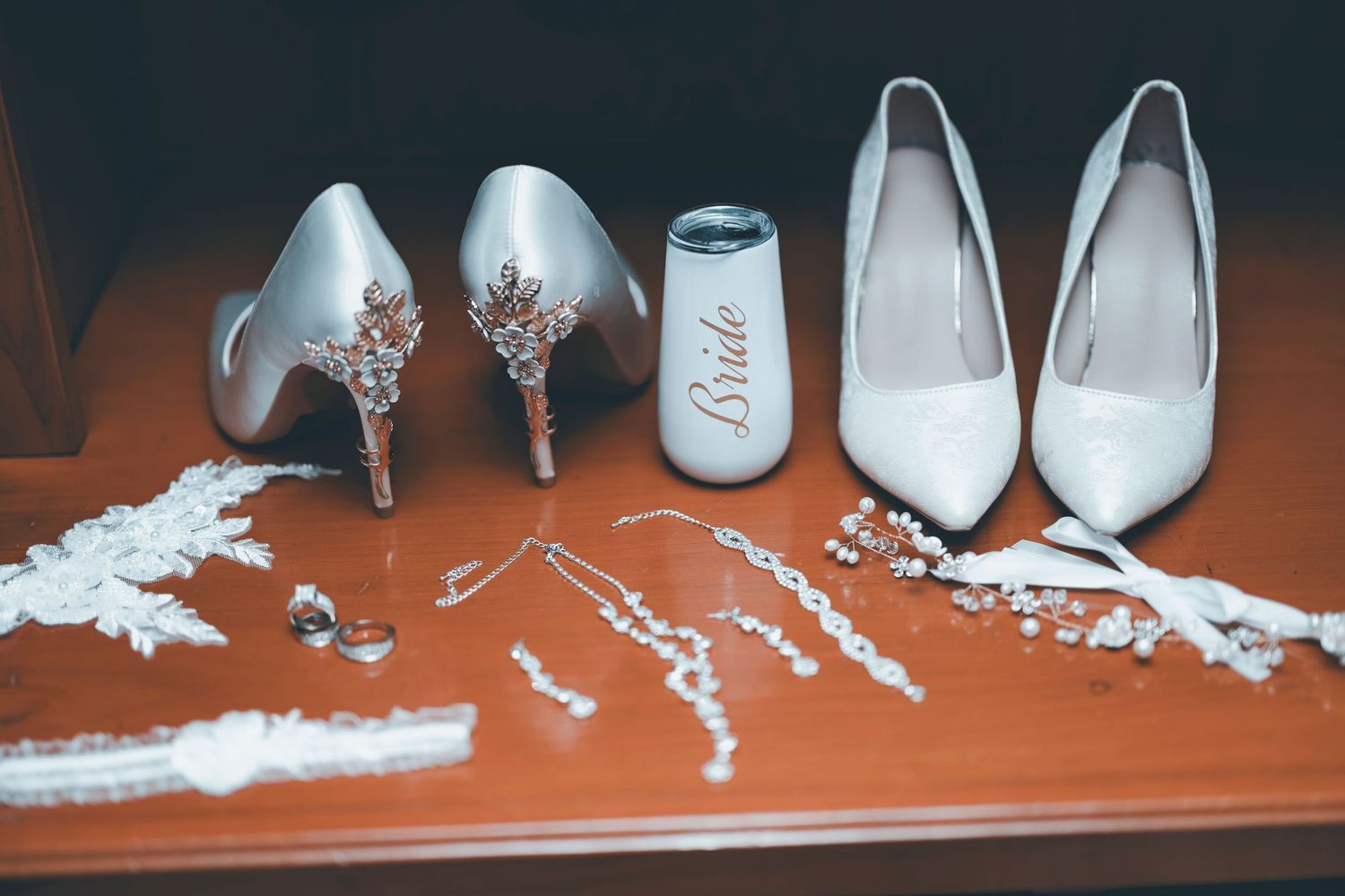 Wedding accessories including white bridal shoes, jewelry, and hair accessories arranged on an orange surface.